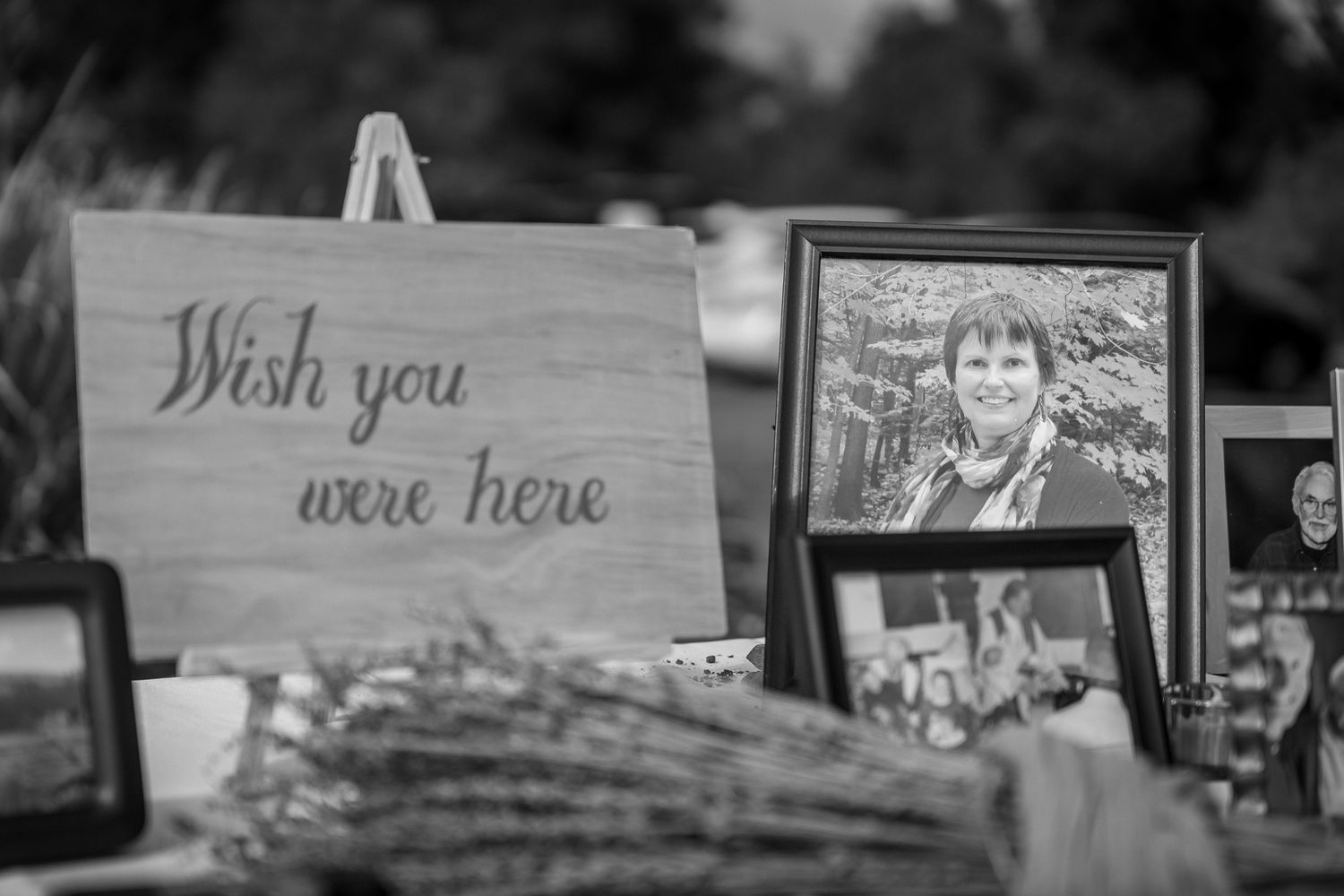 A wooden 'Wish you were here' sign sits beside framed photographs in a black and white arrangement.