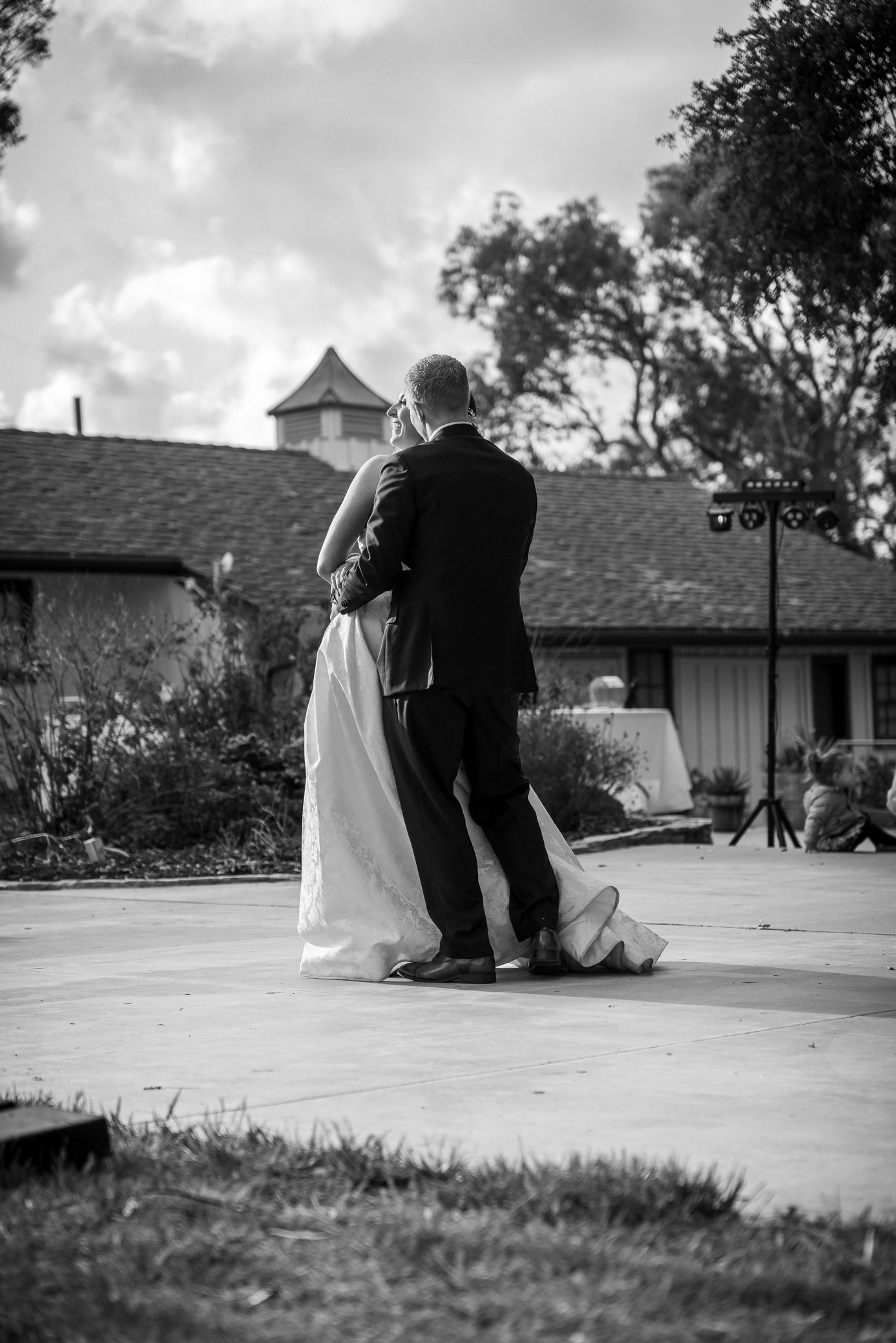 A couple shares an intimate dance moment on an outdoor patio during a black and white wedding celebration.