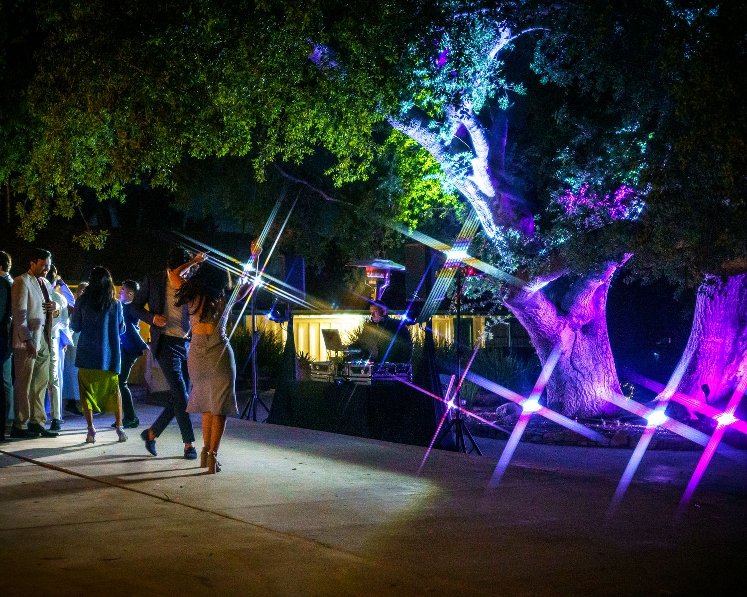 Colorful illuminated art installation with glowing crosses and purple lights displayed at night as people observe the display.