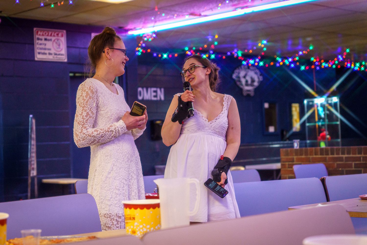 Two people in white attire dancing together on an illuminated dance floor with blue and purple lighting effects.