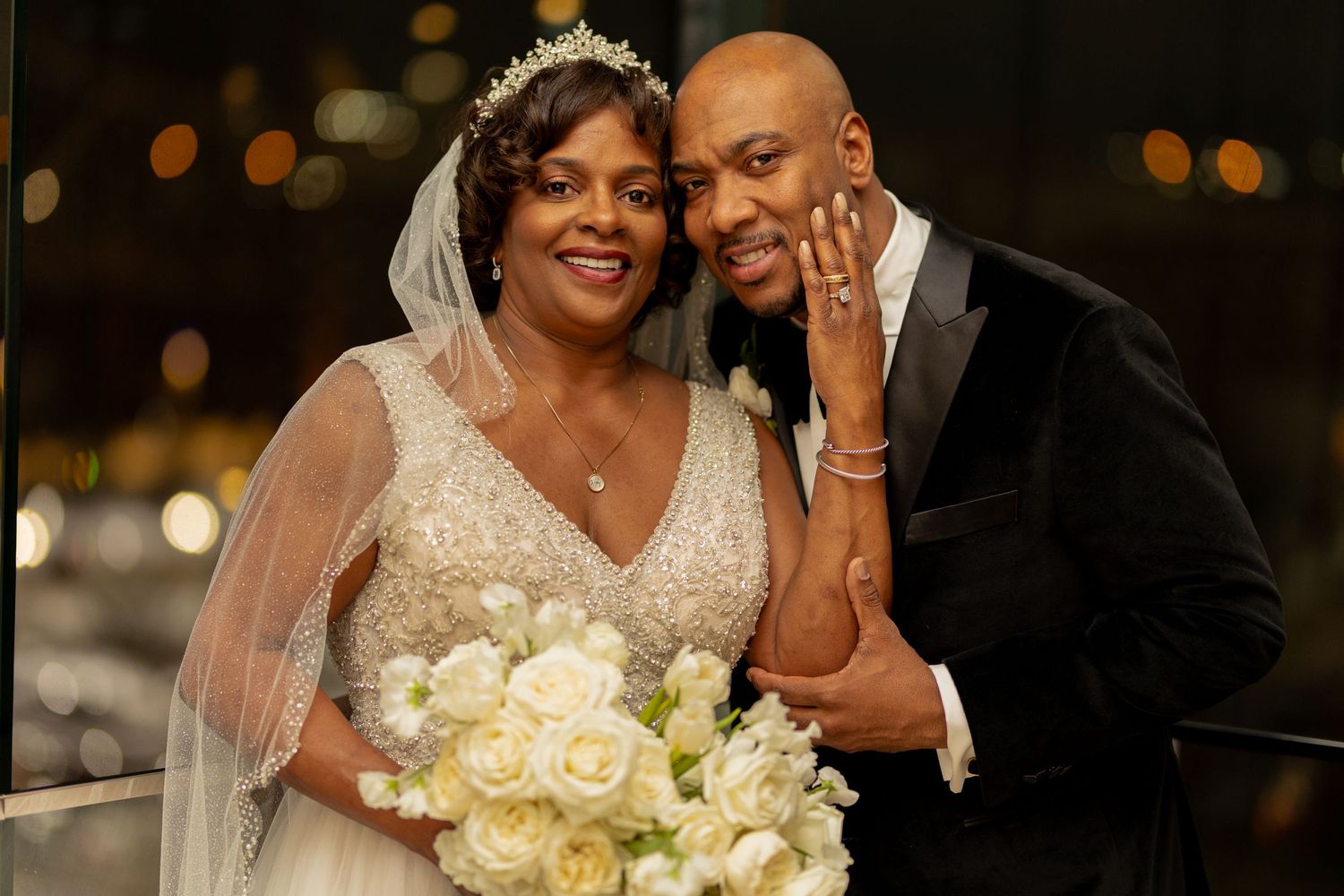 A joyful wedding couple shares intimate moments during their reception with beautiful bokeh lighting in the background.