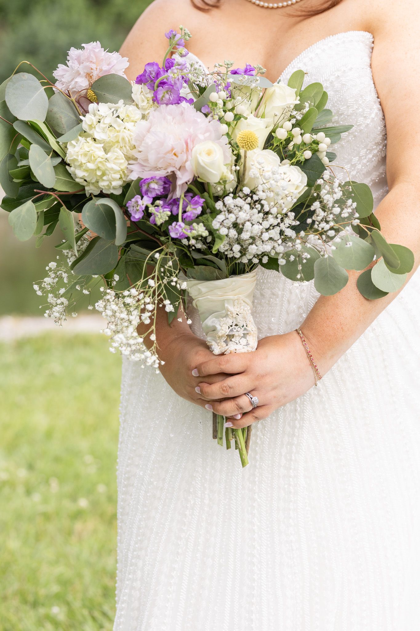 A bridal bouquet featuring white hydrangeas, pink roses, purple wildflowers, baby's breath and eucalyptus leaves.