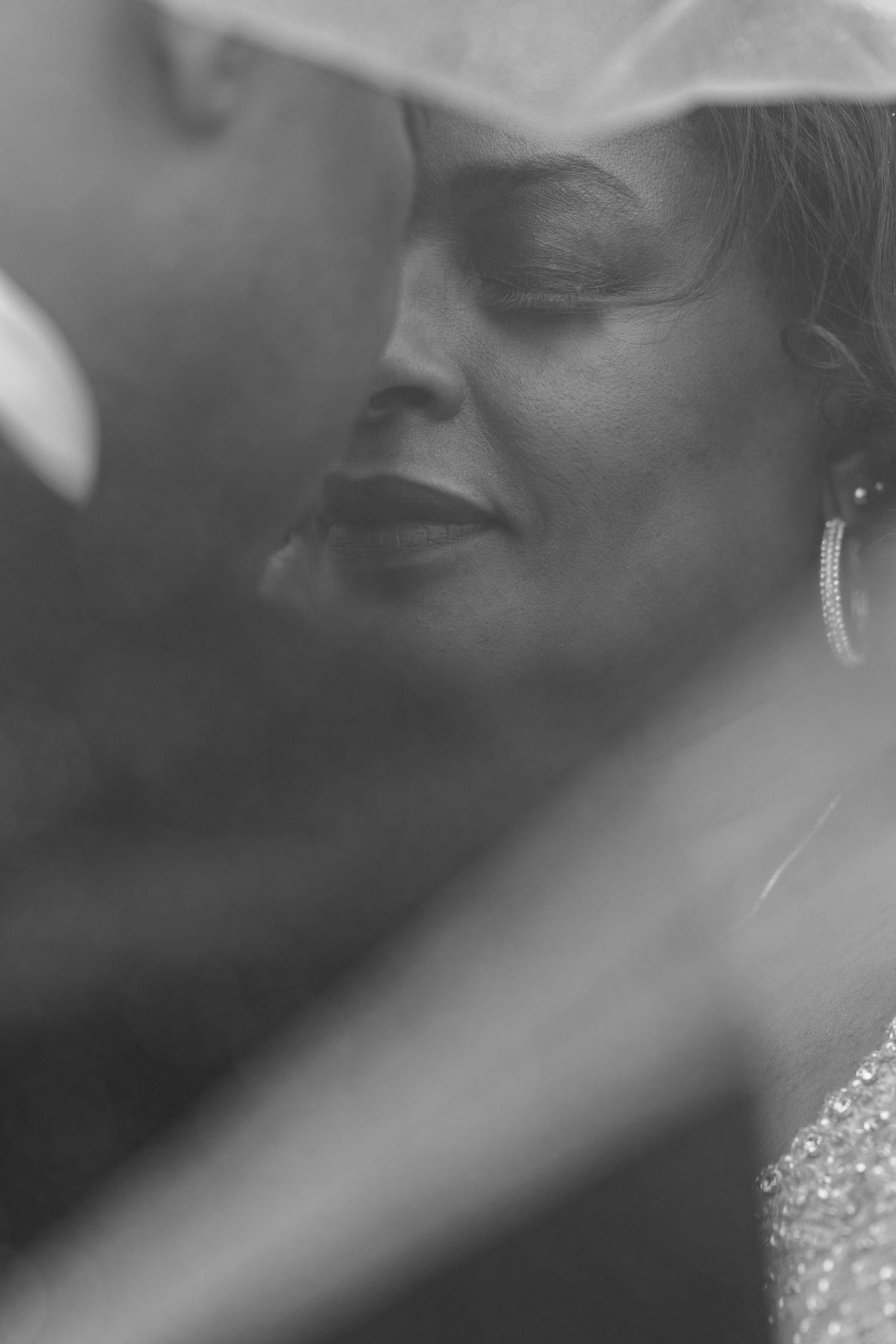 Artistic black and white close-up portrait of bride wearing earrings and veil.