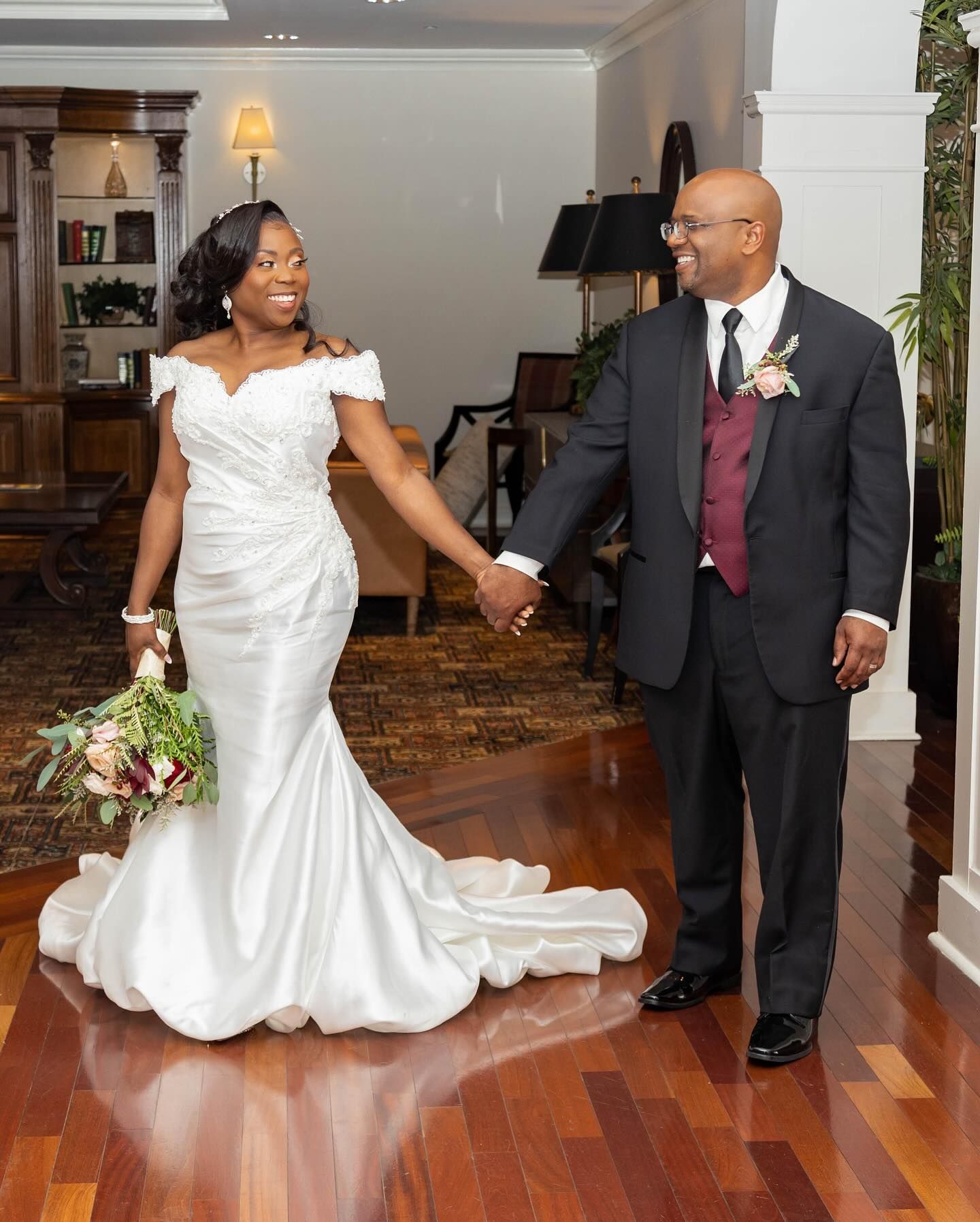 Wedding couple sharing happy moment on hardwood floor in elegant indoor setting.