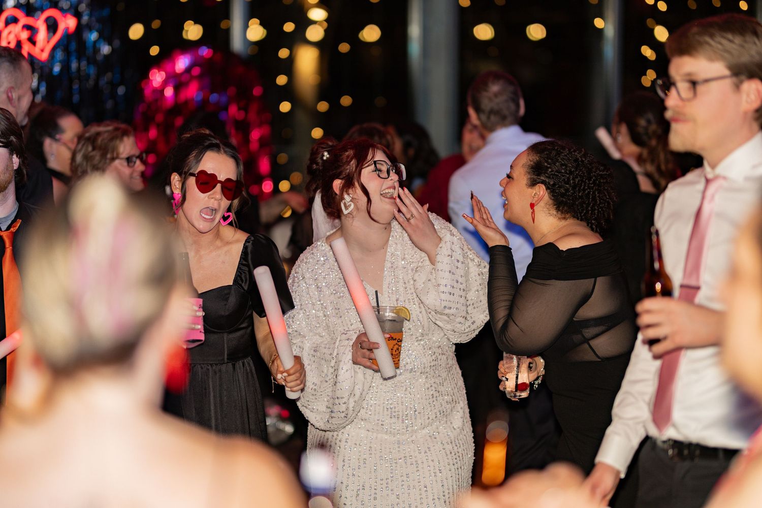 Wedding reception dance floor with guests celebrating under colorful lights.