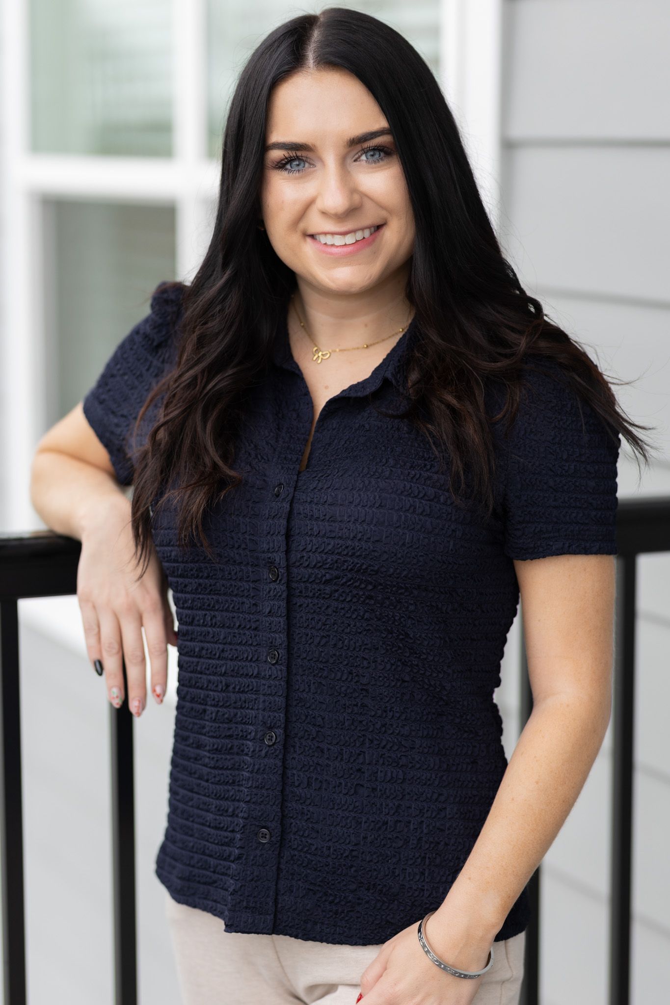 Professional profile photo of someone in a navy blue textured button-up shirt against a light background.