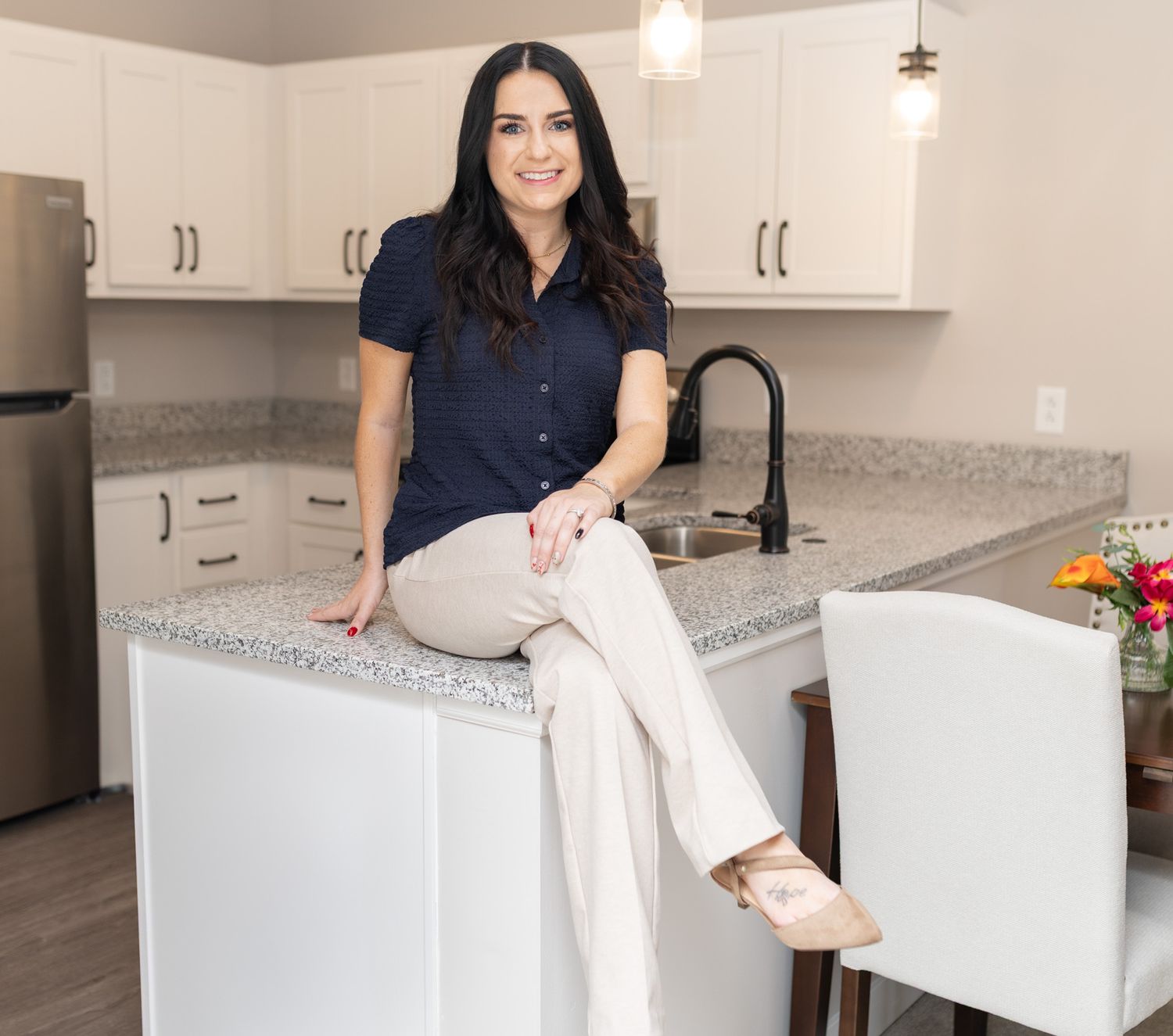 Person in navy shirt sitting casually on white kitchen counter.