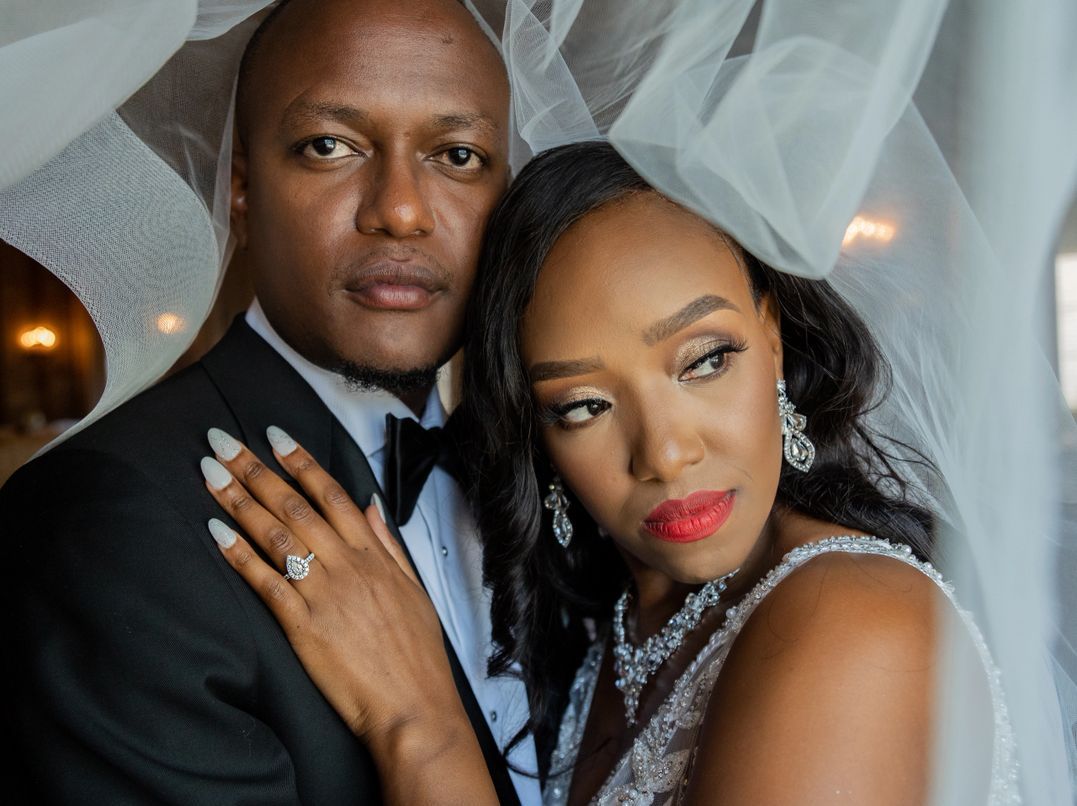 A wedding portrait of newlyweds in formal attire with beautiful veil detail.