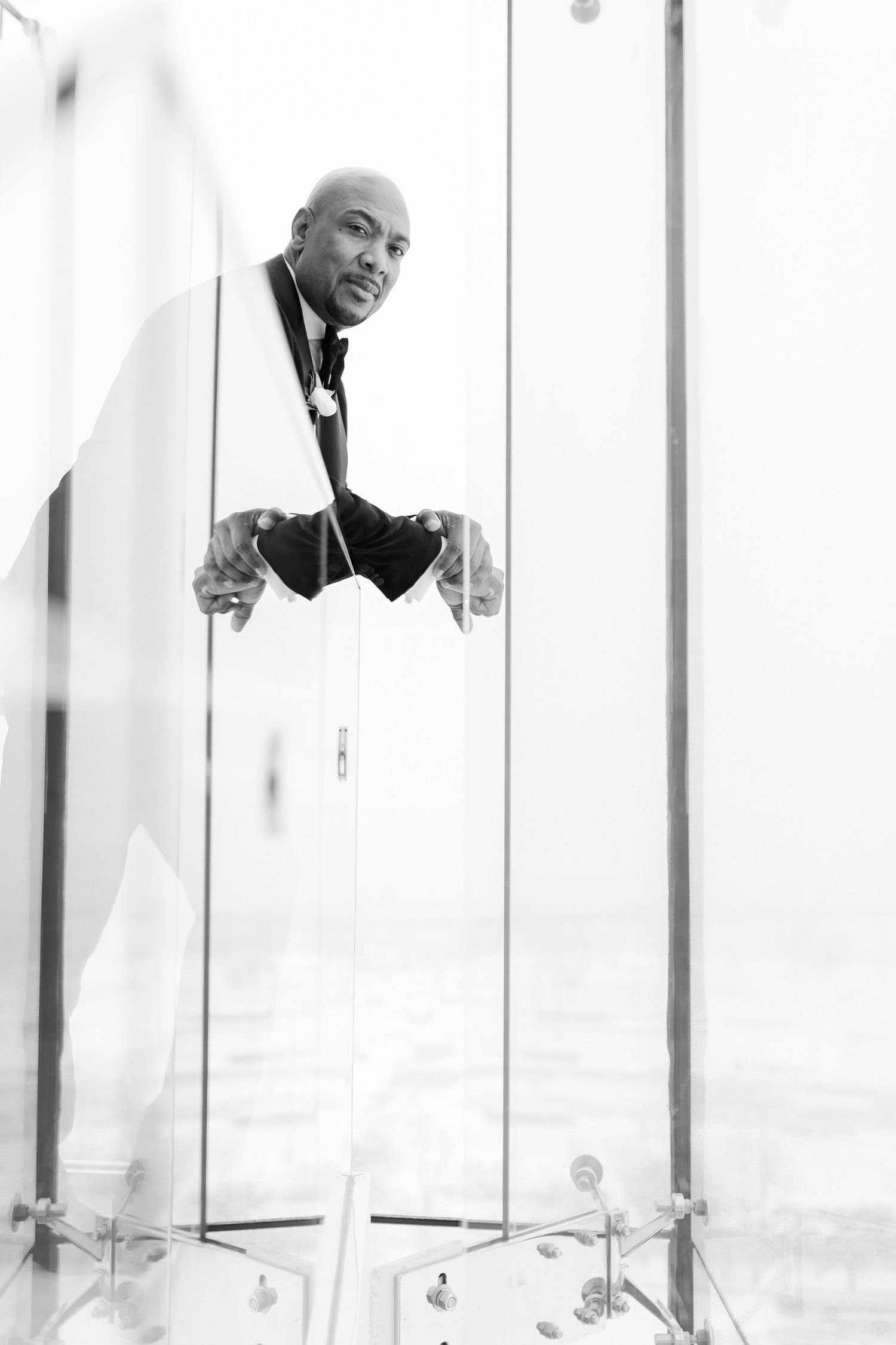 Artistic black and white portrait of a groom looking through modern architectural elements.