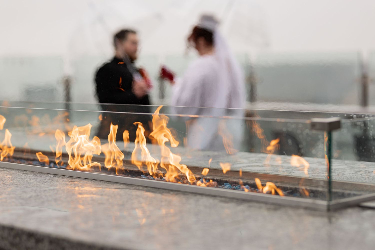 Modern fire feature creates dramatic wedding atmosphere with couple silhouetted in background.