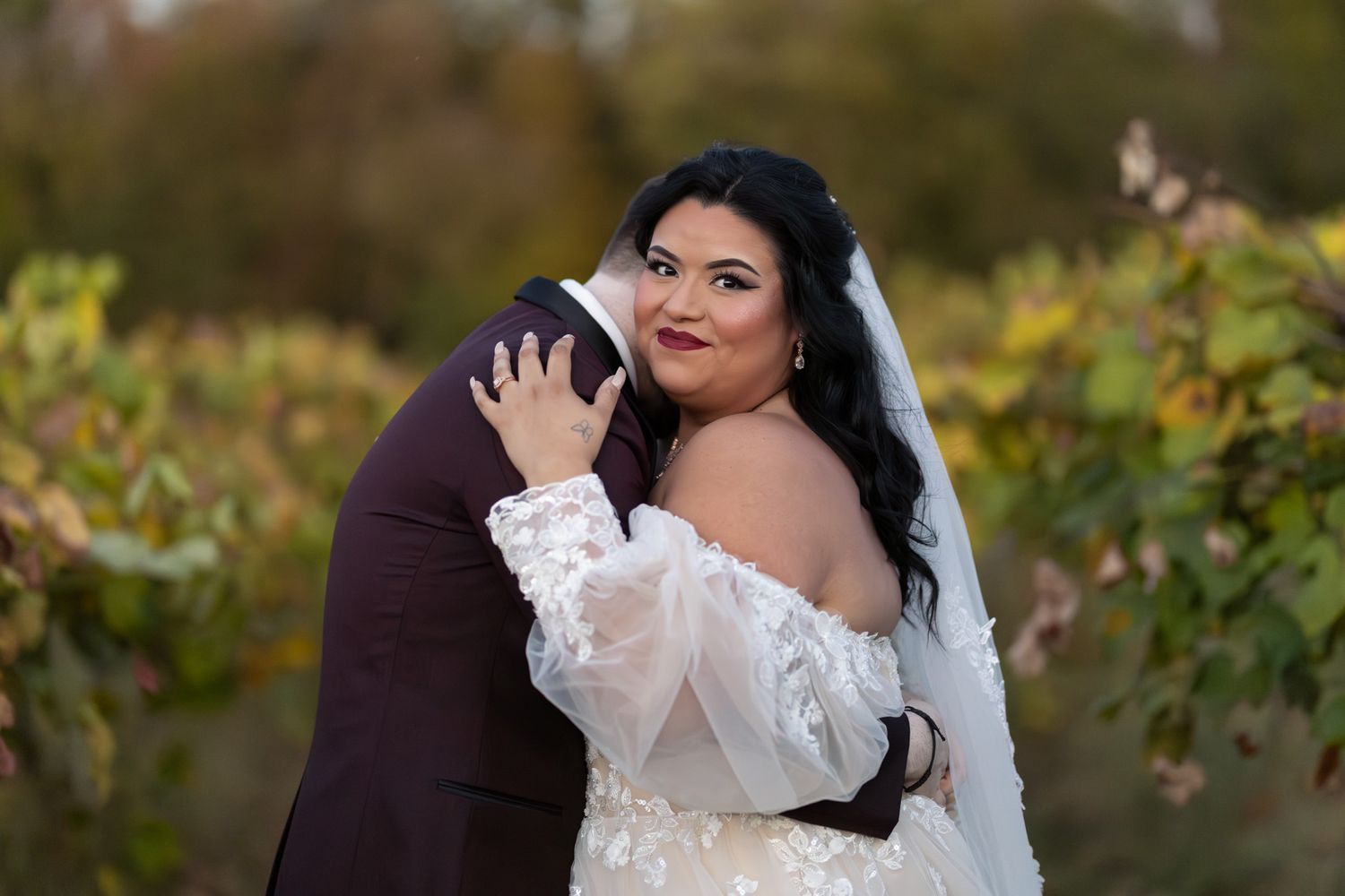 An intimate embrace between newlyweds in a fall vineyard setting.