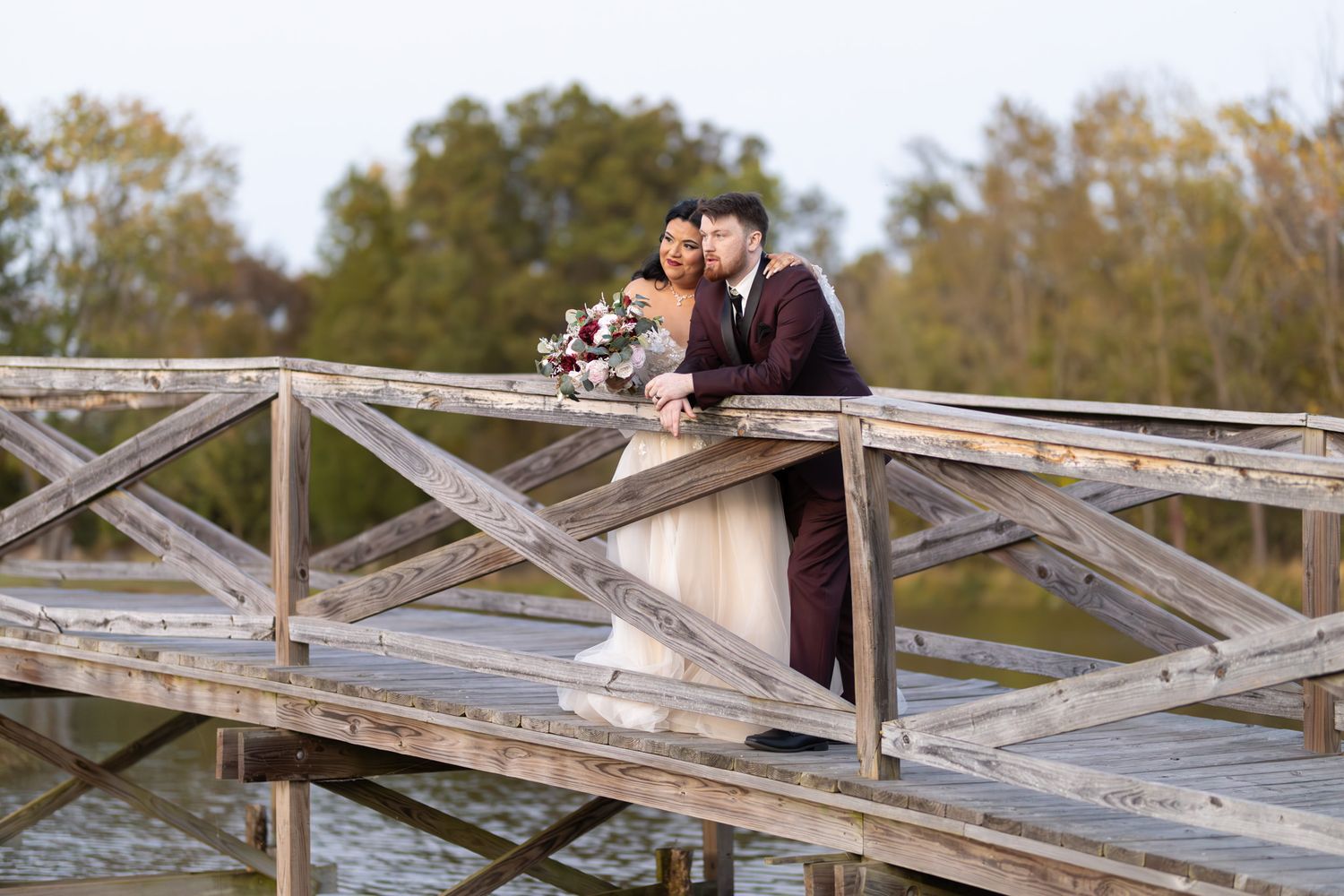 Wedding couple standing together on a rustic wooden bridge.