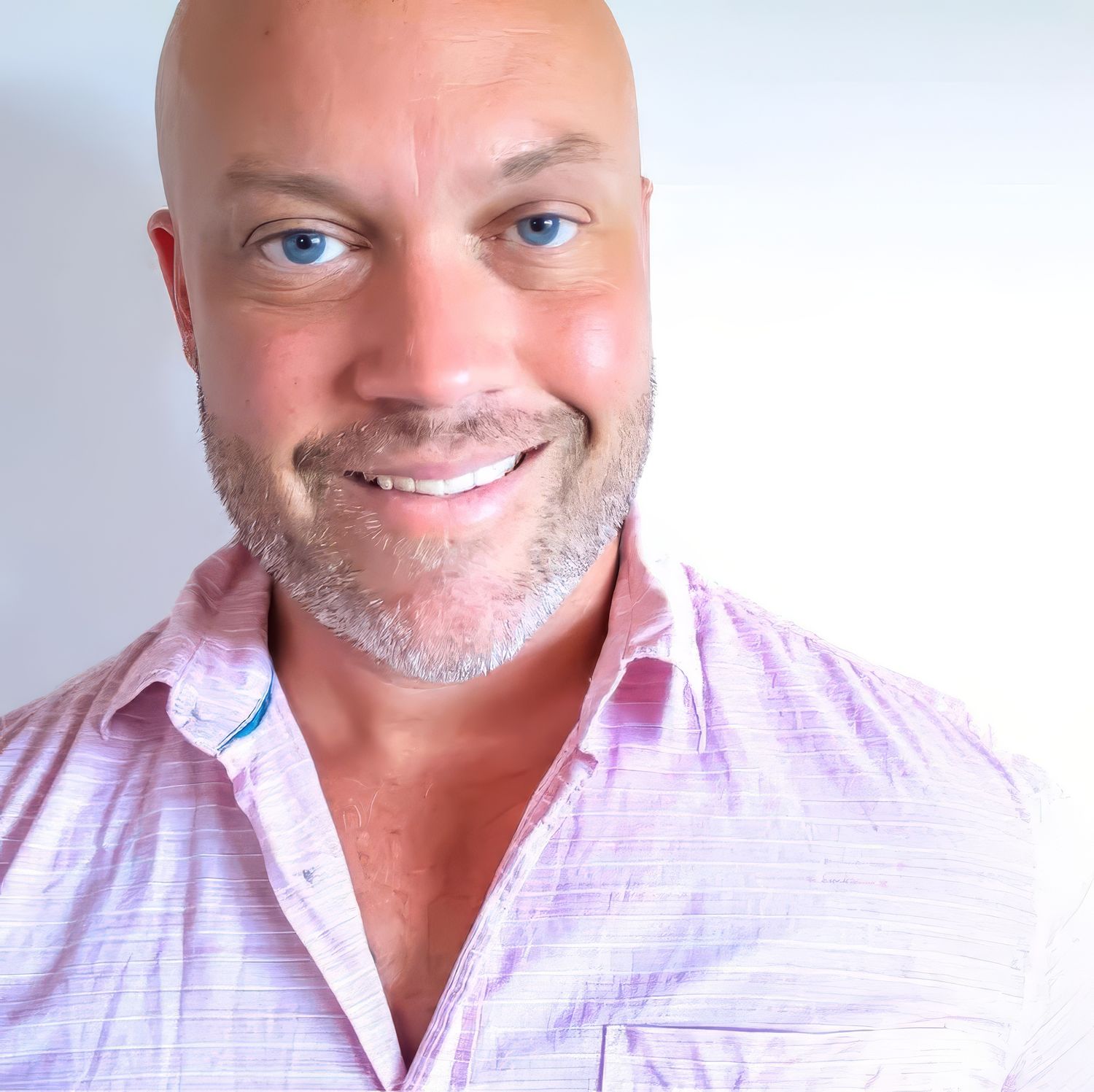 A smiling man wearing a light pink button-down shirt poses against a white background.