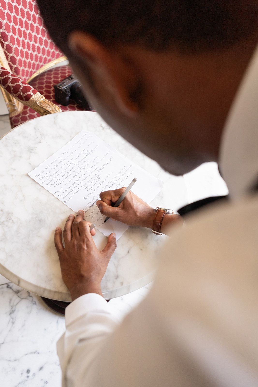 Close-up view of hands writing on white paper while wearing a crisp white dress shirt.
