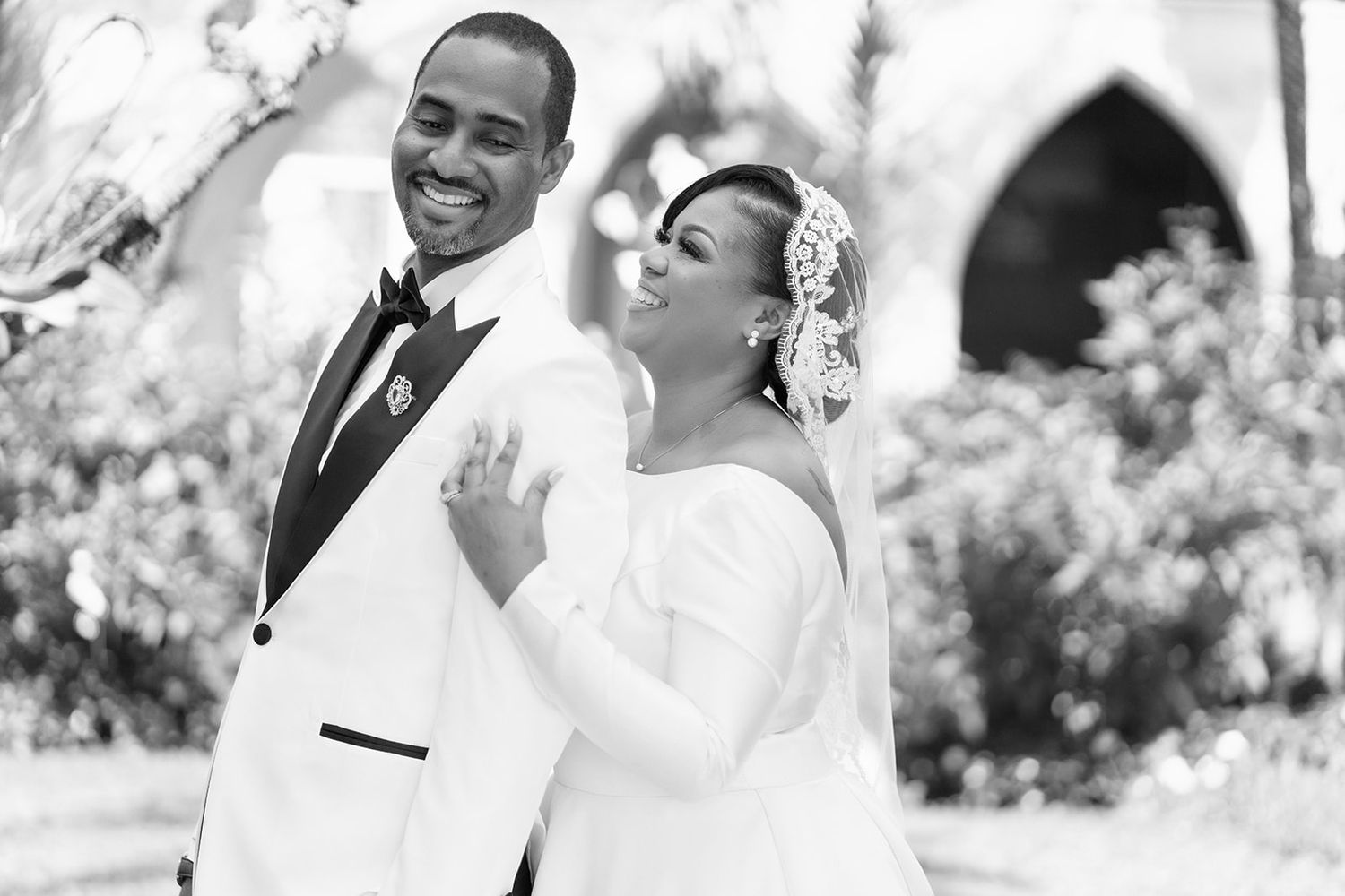 An elegant black and white portrait of a wedding couple in formal attire.