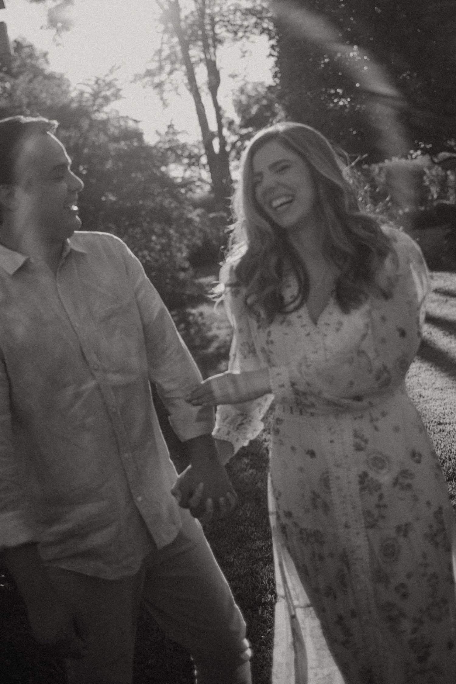 Two people share a joyful moment together outdoors in a black and white photograph.