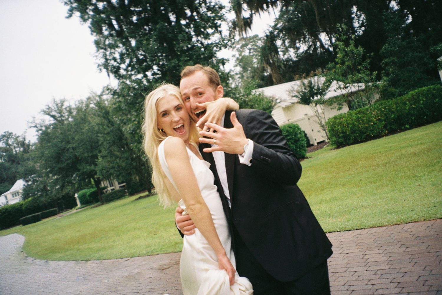 A couple in formal wedding attire shares an intimate moment together in an outdoor garden setting.