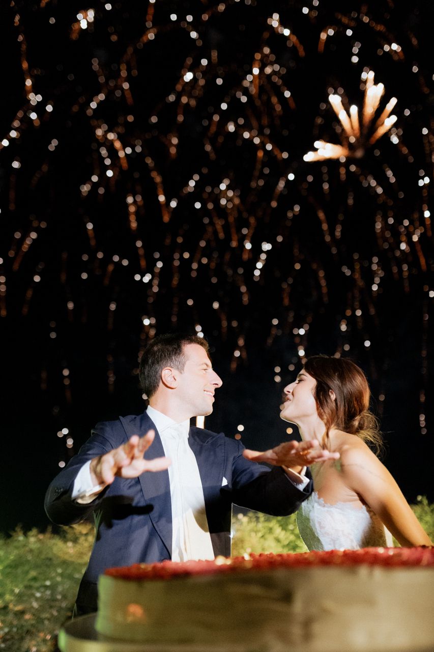 Wedding couple shares joyful moment under fireworks display.