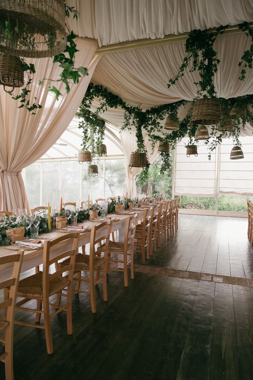 Romantic wedding reception venue with draped fabric ceiling and hanging greenery decorations.