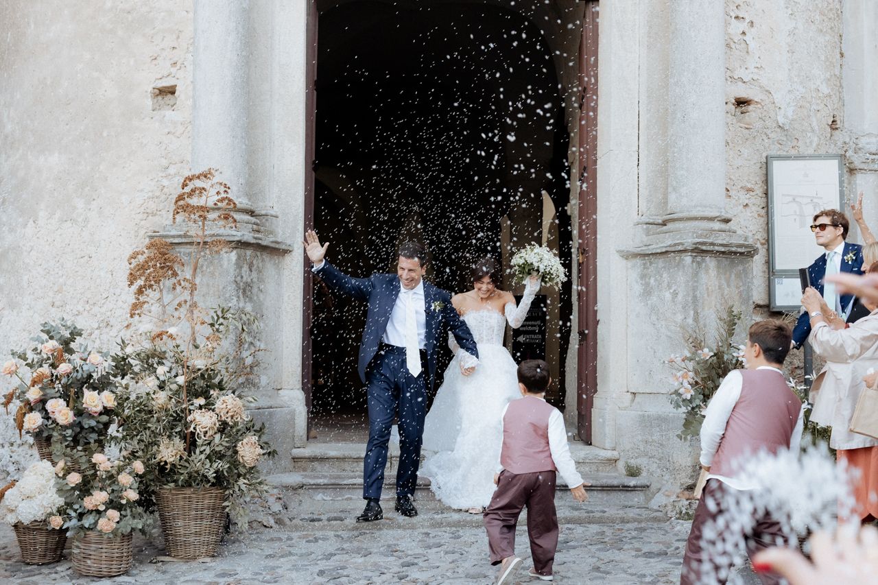 Wedding couple exits church doors as guests throw confetti in celebration at a traditional ceremony.
