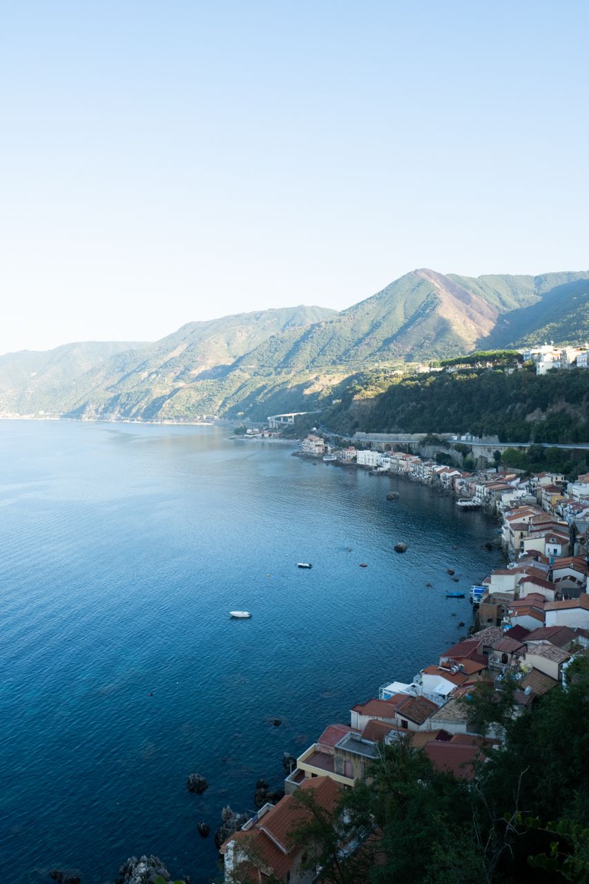 Coastal Mediterranean village nestled along mountainous shoreline with blue waters.