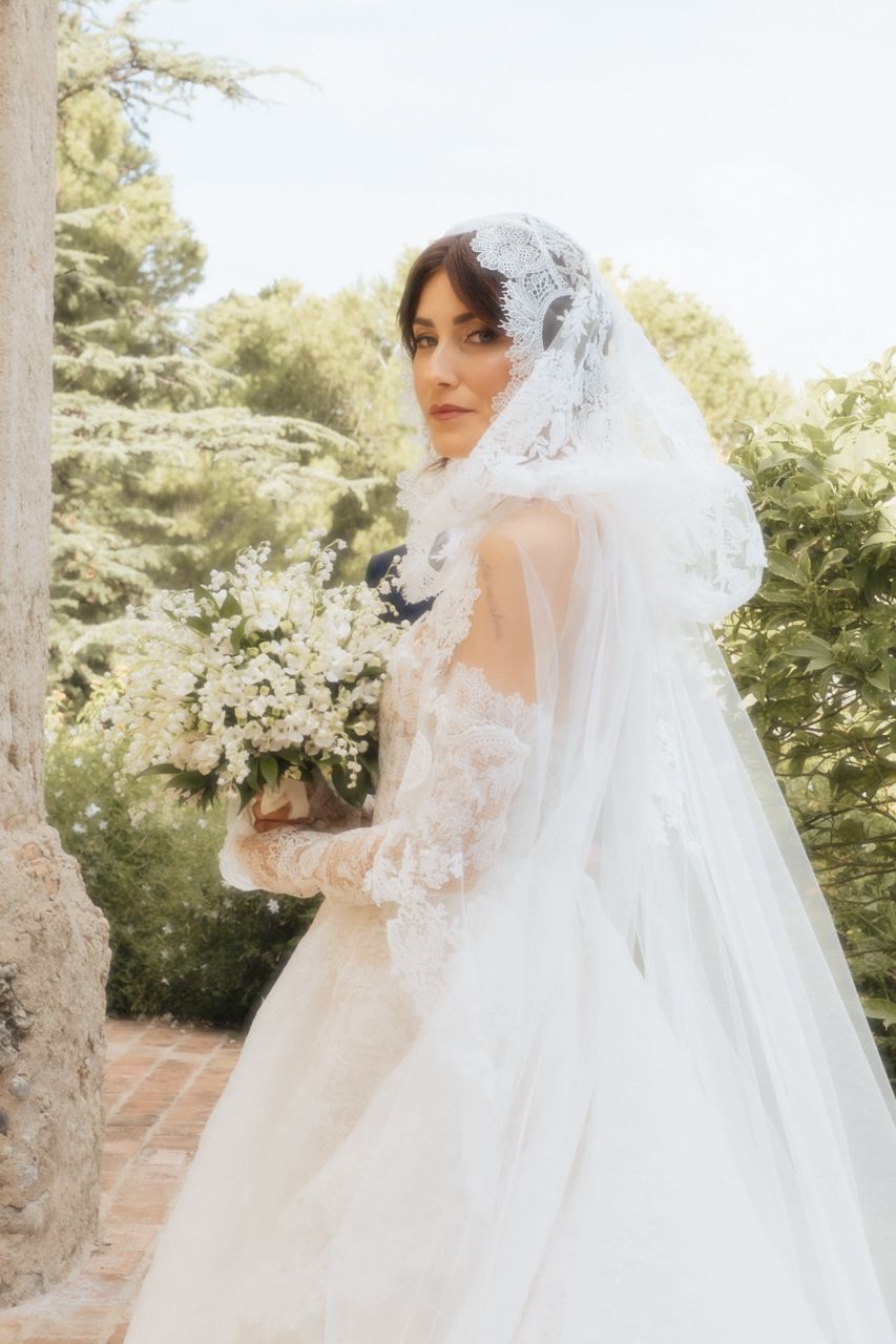 A stunning outdoor bridal portrait featuring a cathedral veil and white floral bouquet.
