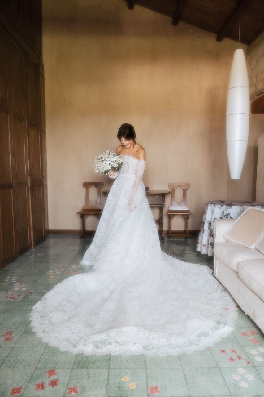 A stunning full-length bridal portrait in a lace gown with cathedral train on a vintage tiled floor.
