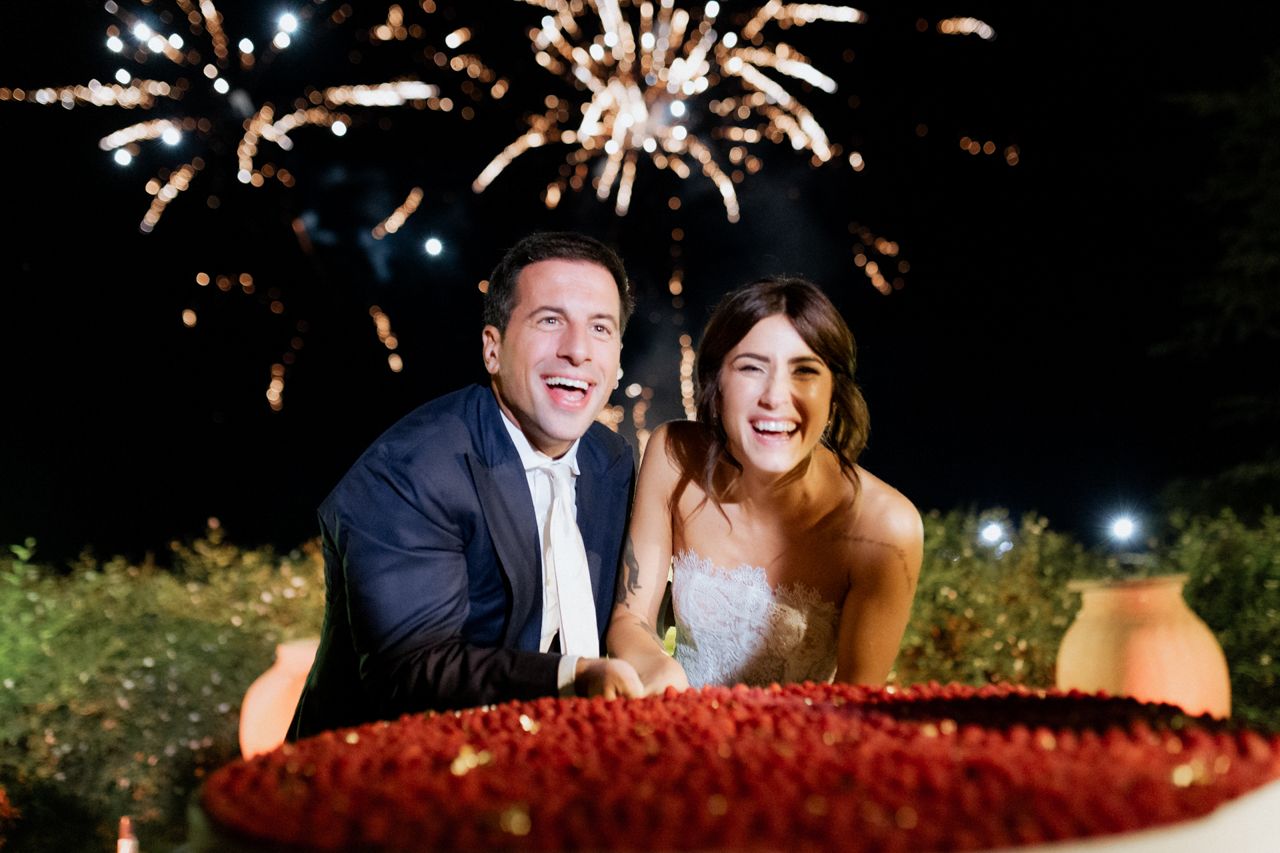 Couple celebrates with sparklers and laughter during wedding reception.