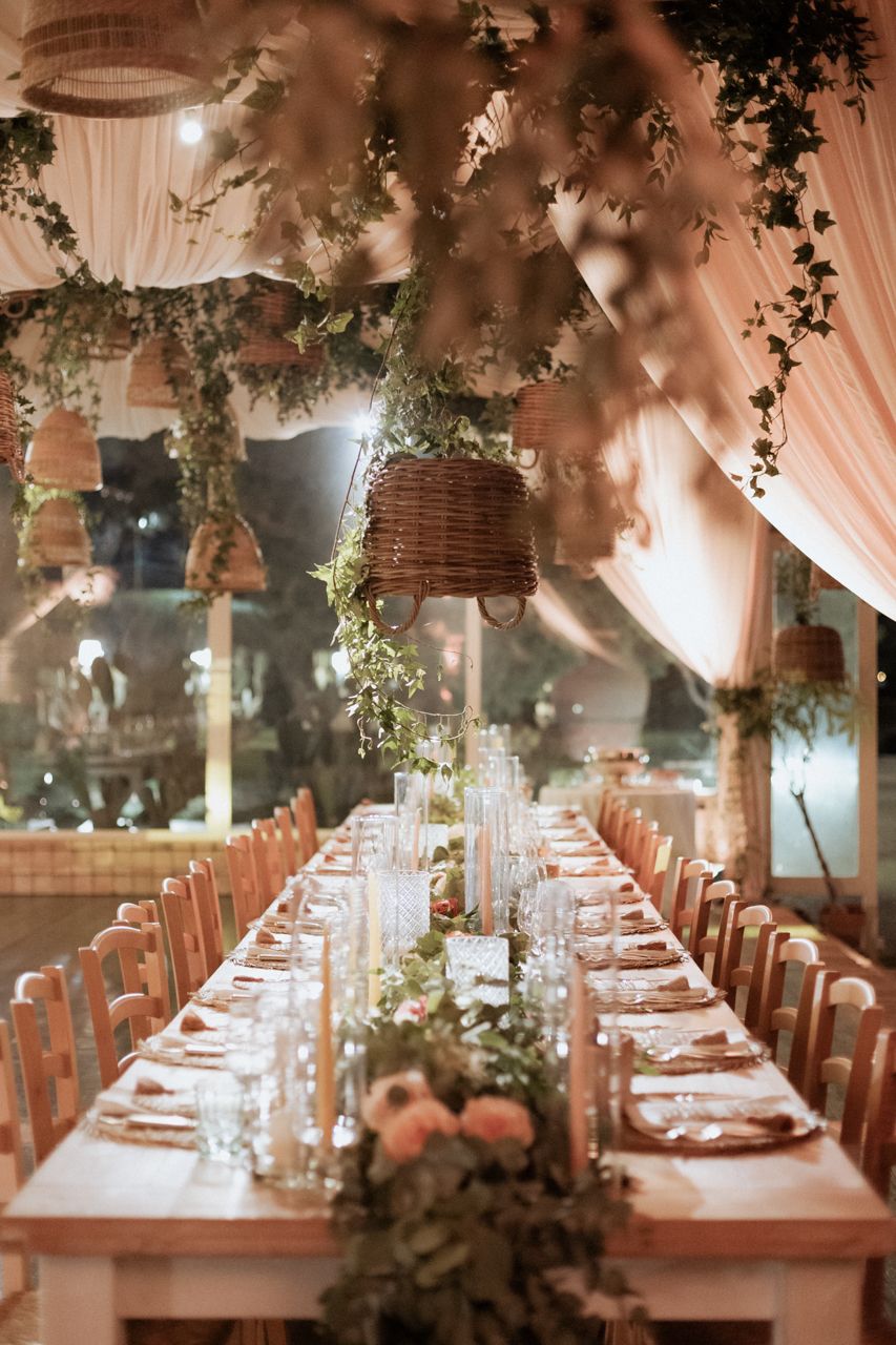 Elegantly decorated wedding reception table with floral centerpieces and draped fabric ceiling.