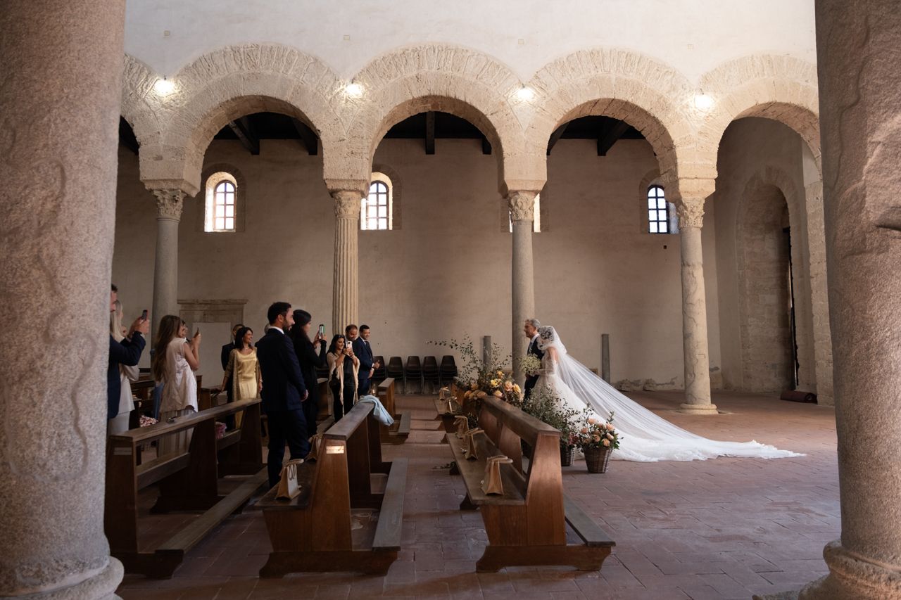 An elegant church wedding ceremony in a historic stone chapel with arched columns.