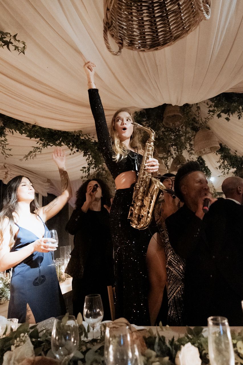 Wedding reception party with live saxophone performance and dancing guests.