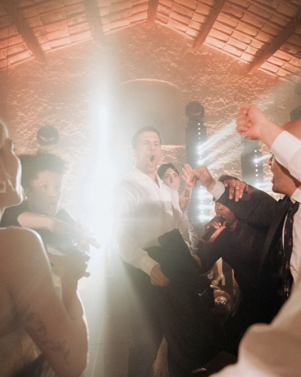 Lively dance floor scene at a wedding reception with bright lighting and energetic celebration.