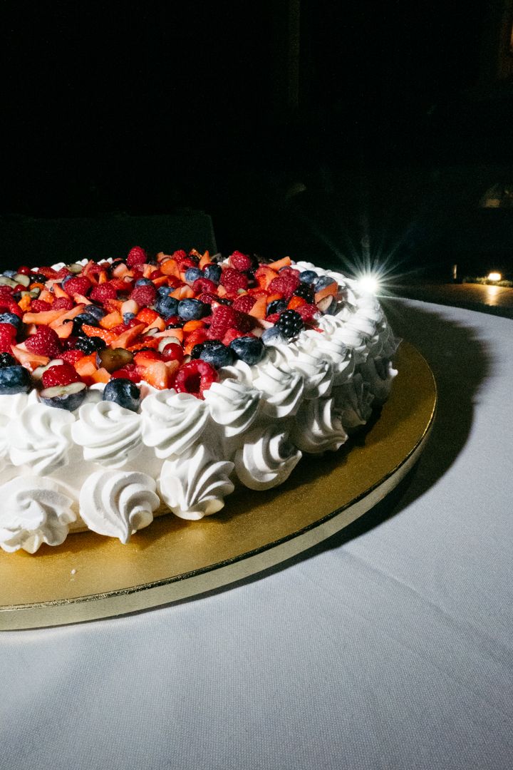 Elegant wedding cake decorated with fresh berries and white whipped cream swirls.