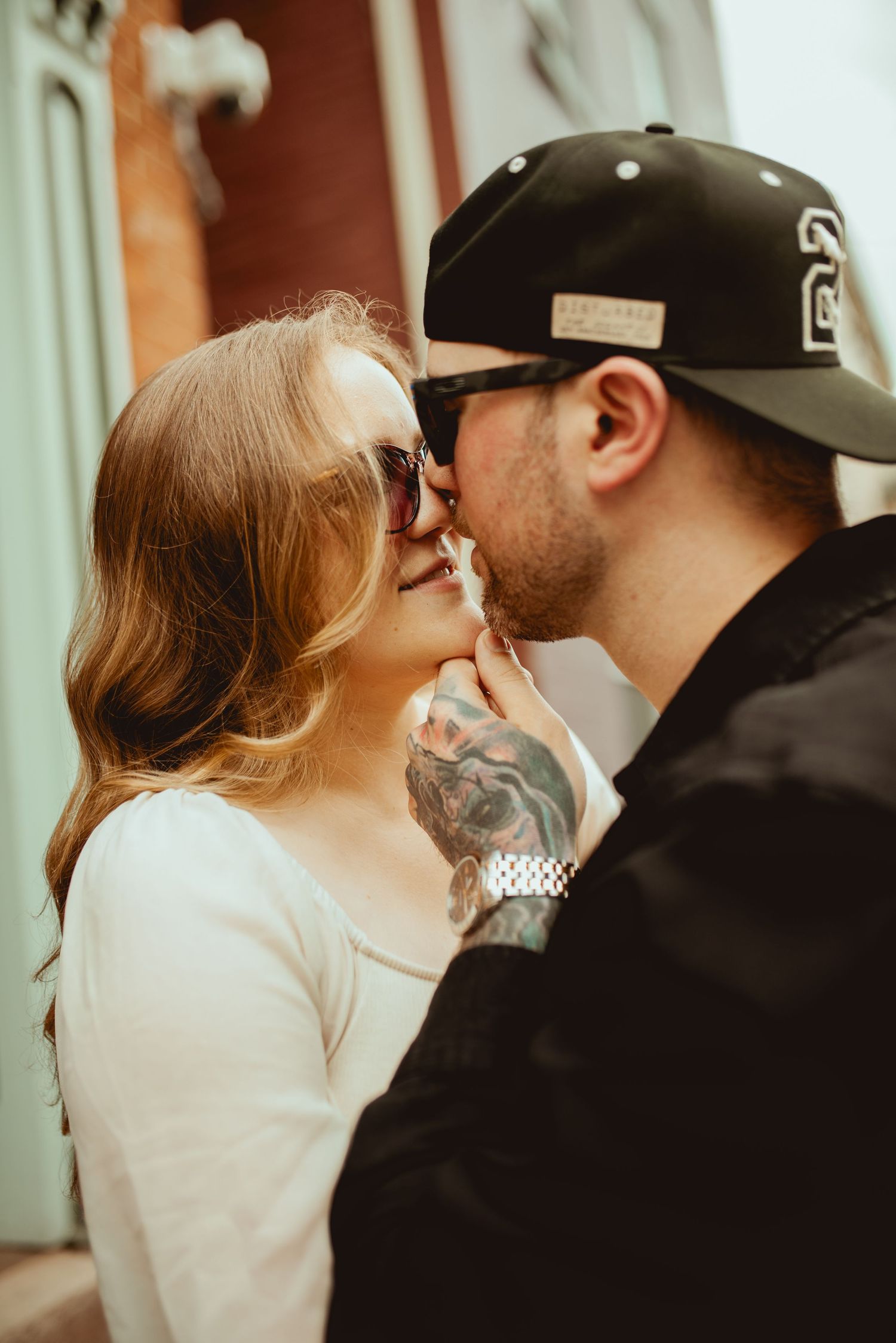 Intimate close-up moment between couple against brick wall background.