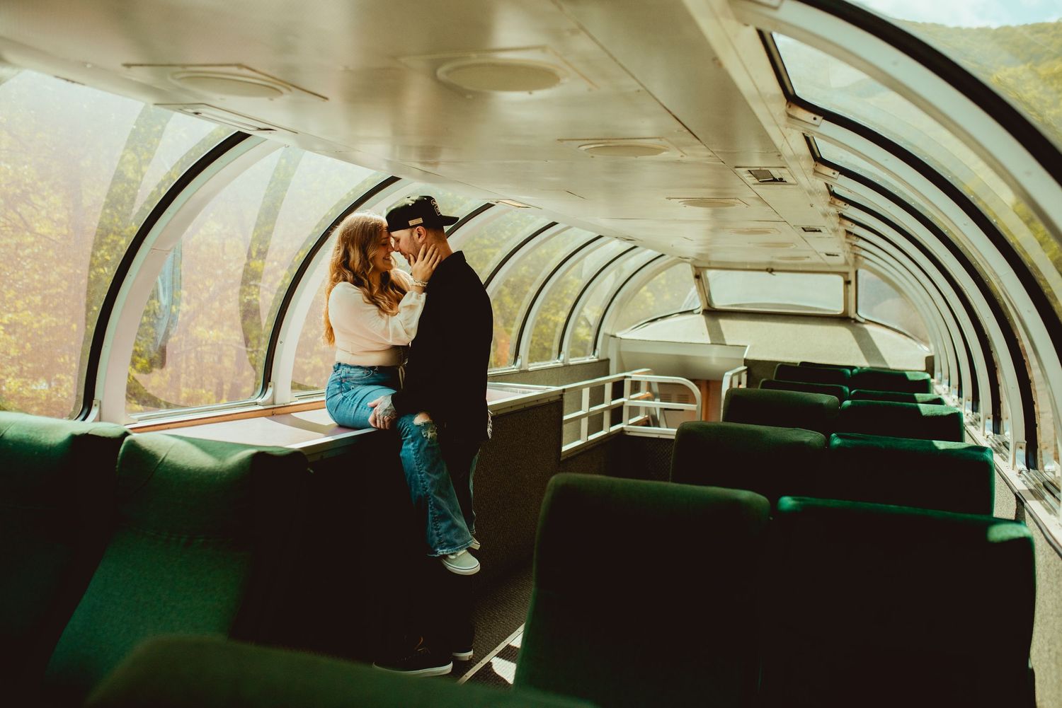 Couple sharing intimate moment in observation car of scenic train.
