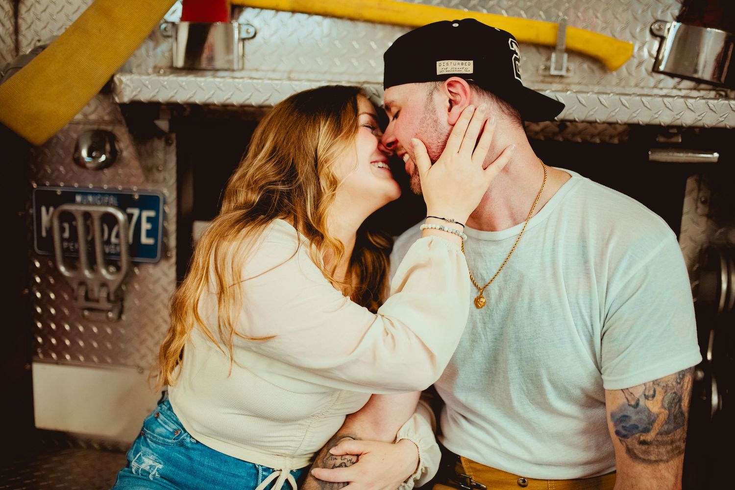 Sweet embrace between couple against fire station equipment.