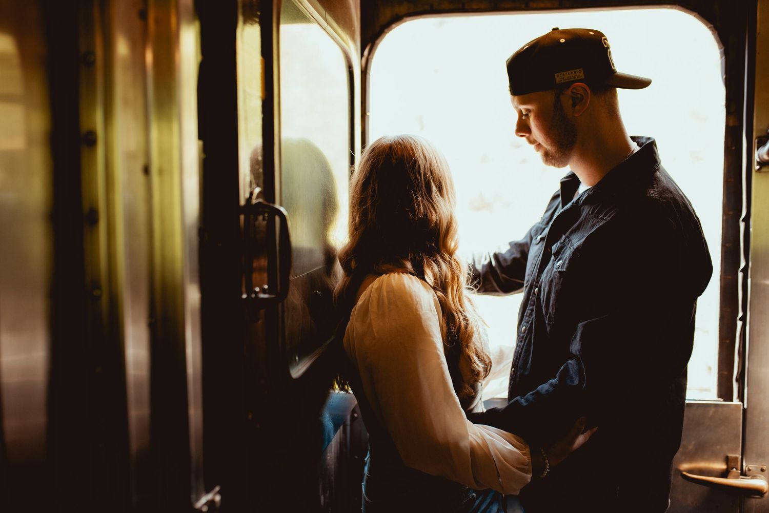 A silhouetted couple sharing an intimate moment inside a train car.