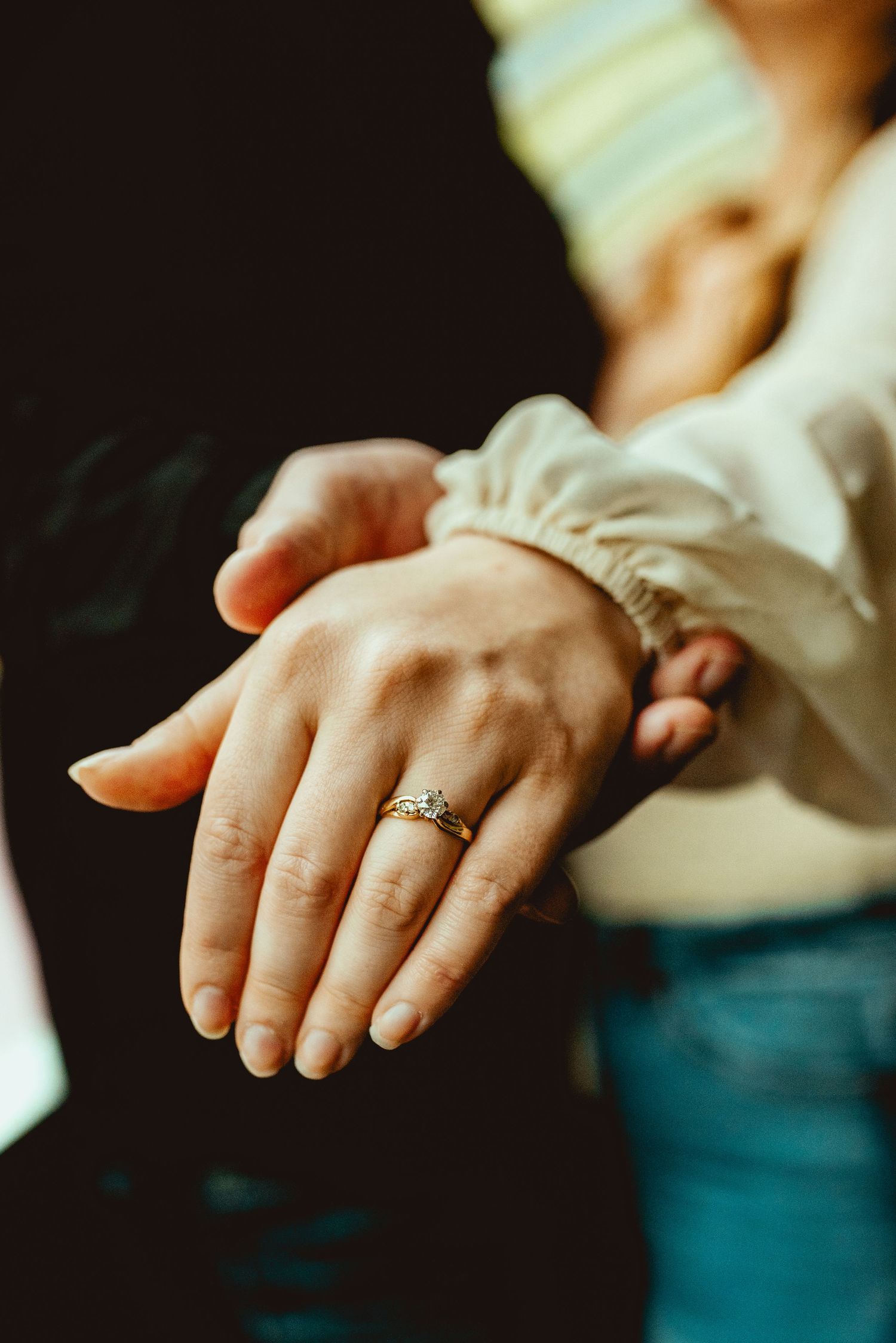 Close-up shot of hands showing an engagement ring in warm lighting.