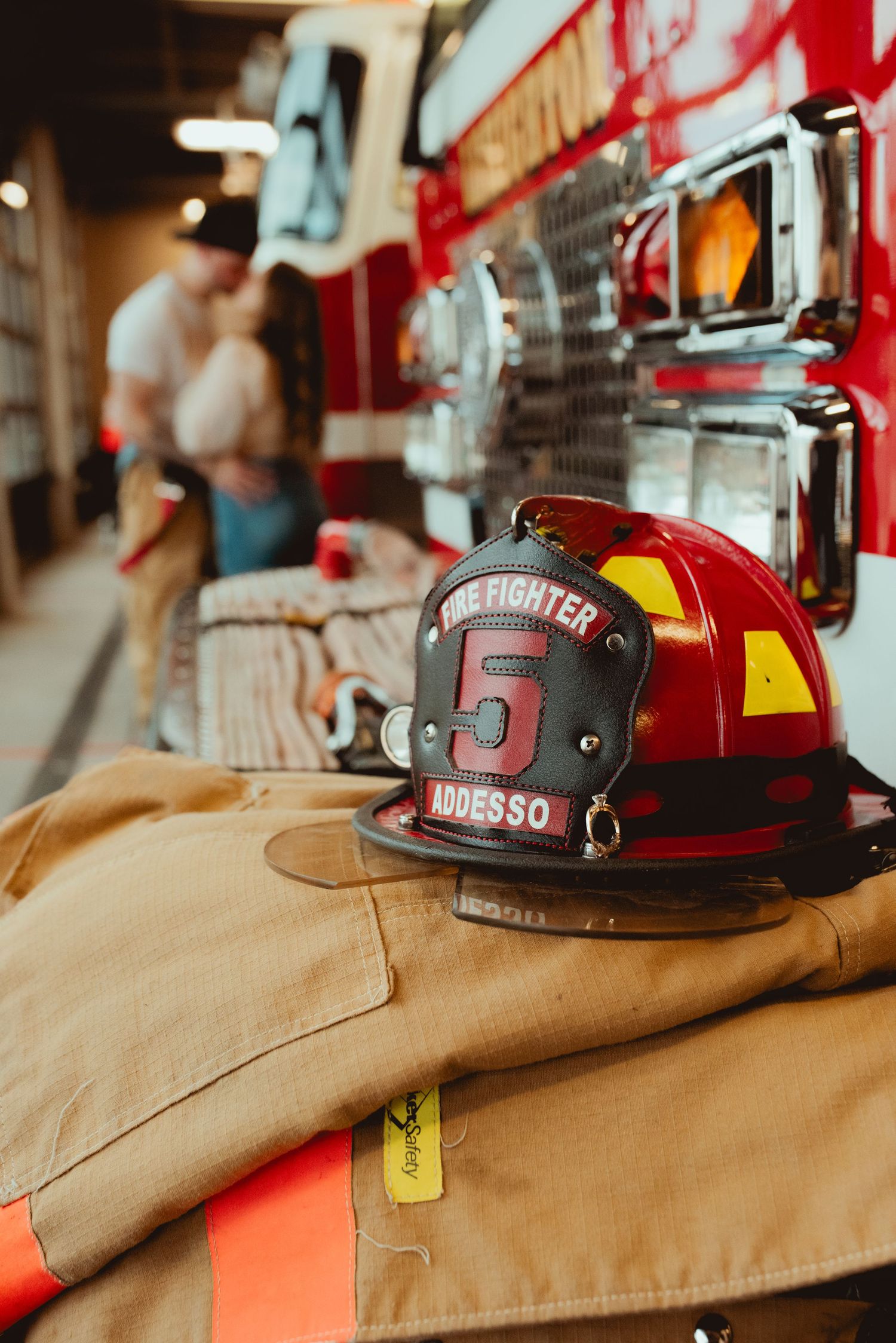 A firefighter's helmet and gear rests on the side of a fire truck in the station.