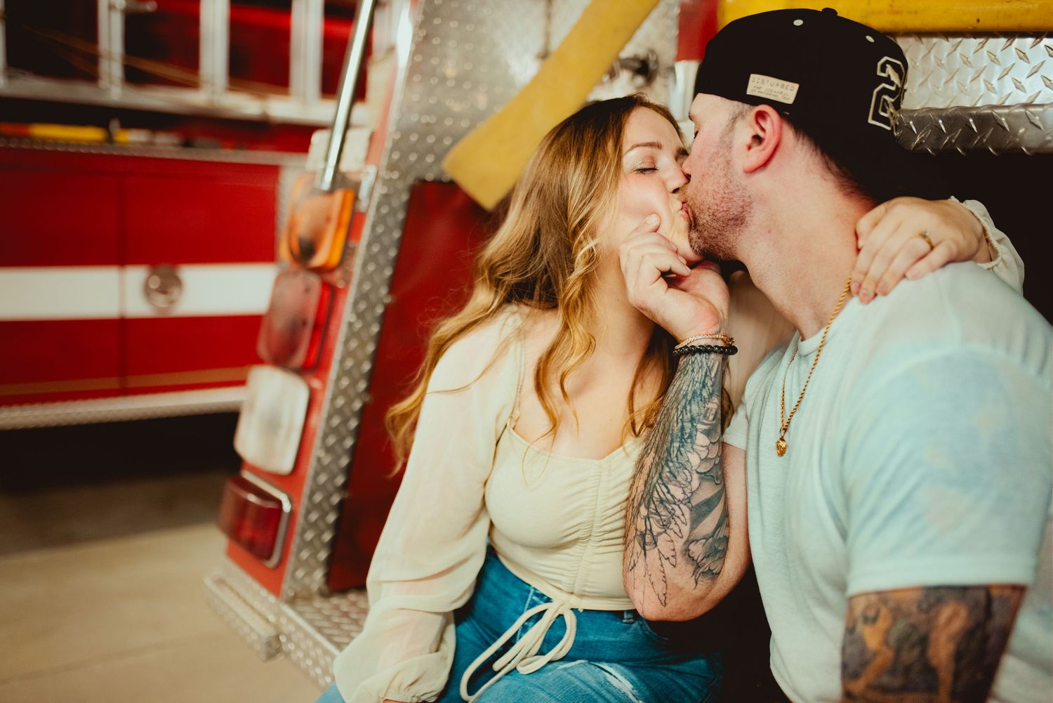 Romantic kiss shared between couple with fire truck in background.
