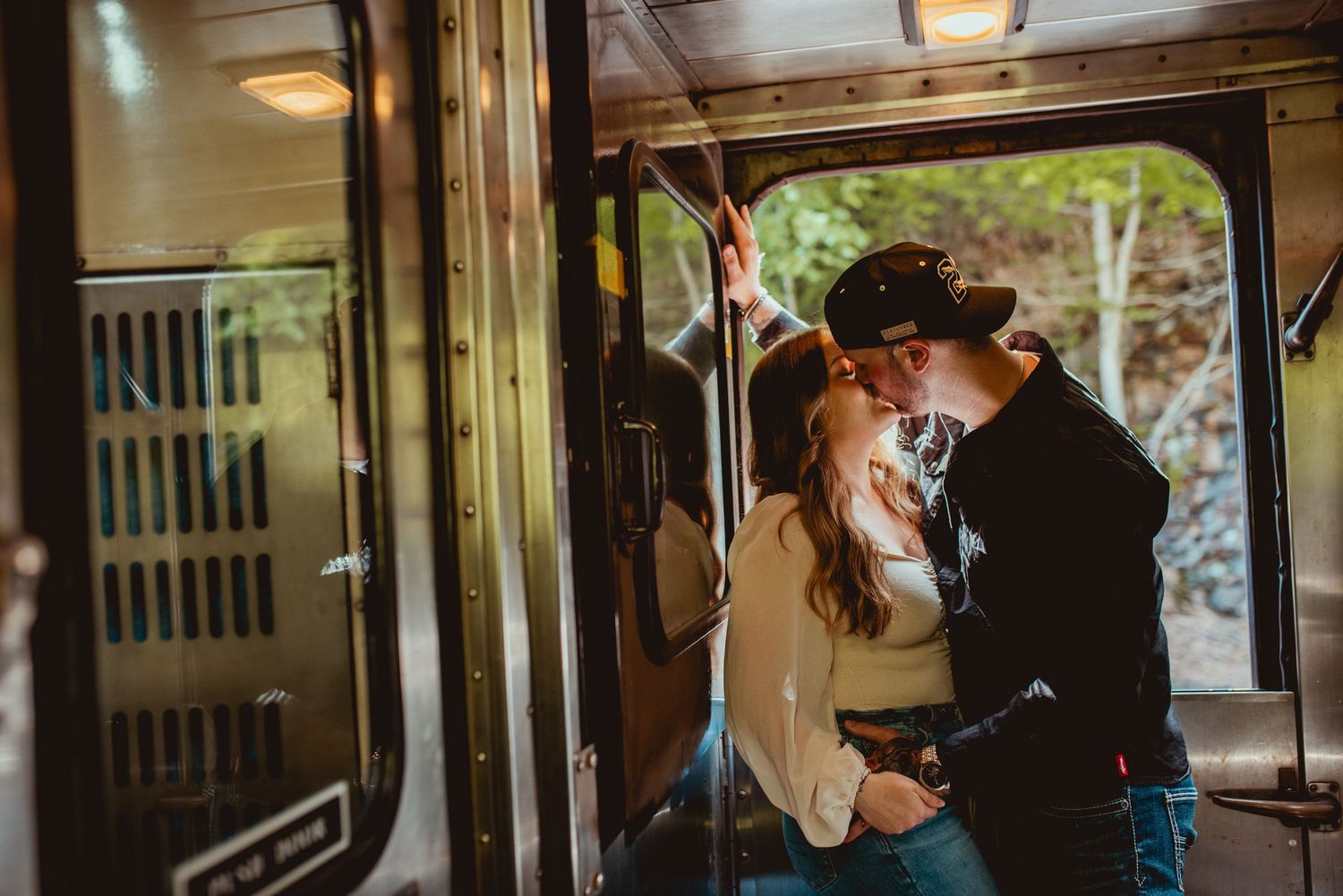 An intimate couples photoshoot inside an old train car with warm lighting.