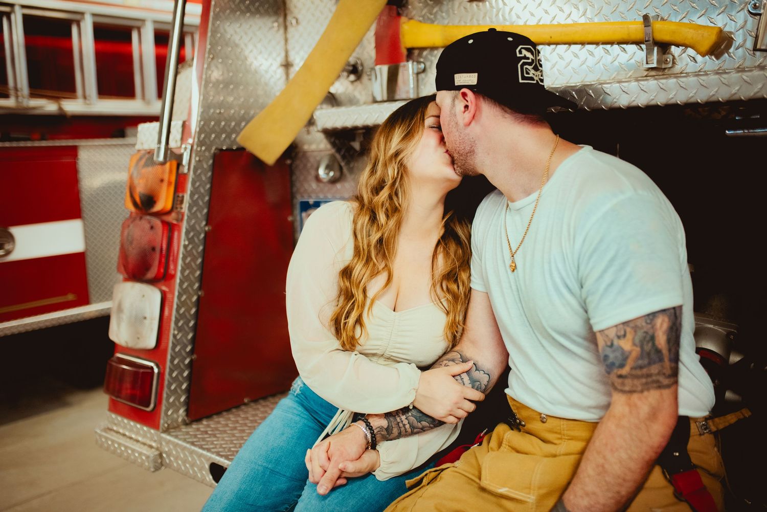Couple embracing intimately against red fire engine backdrop.