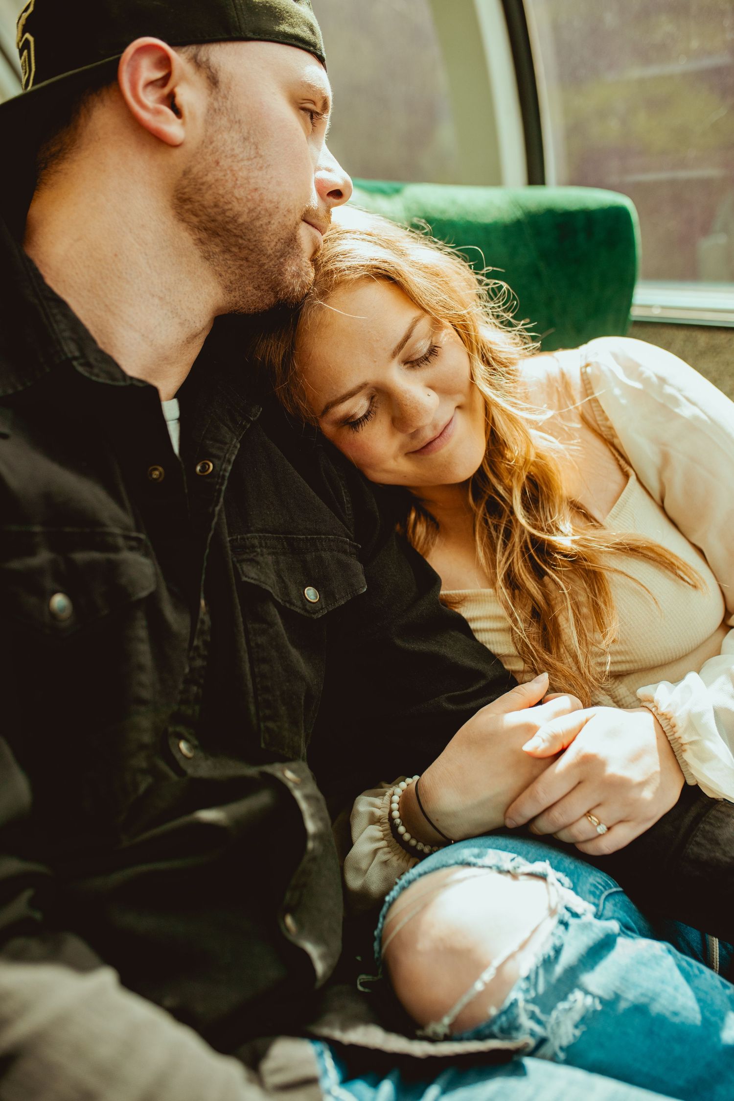 Intimate moment between couple in casual wear on train journey.