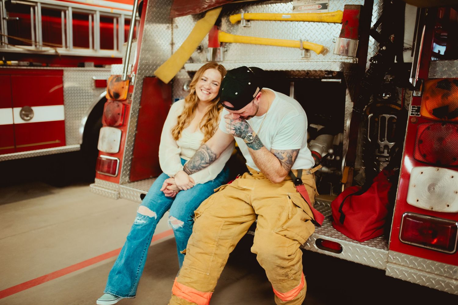 Romantic couple sharing a tender moment on a fire truck at the station.