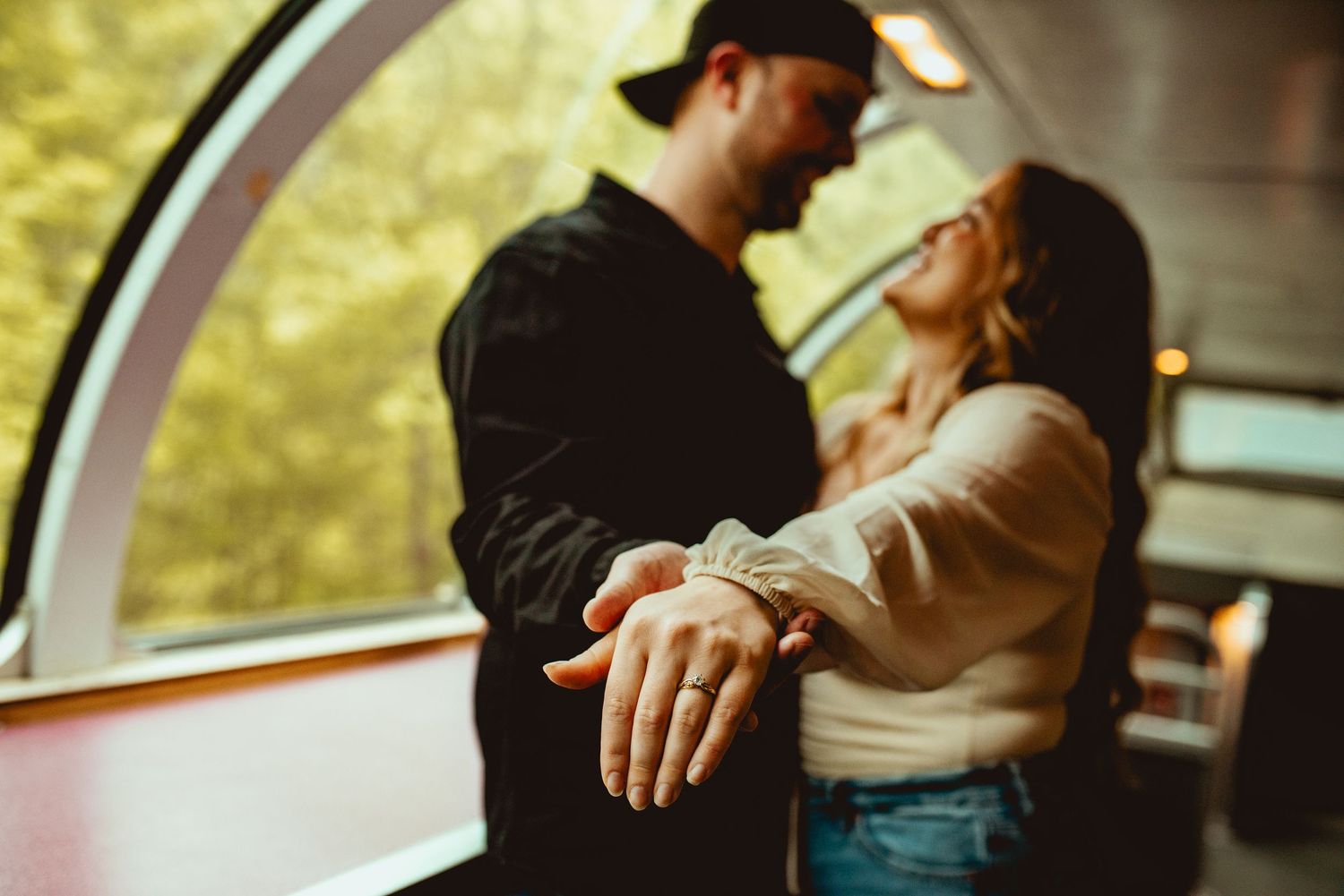 Passengers share an intimate moment aboard a classic train car with curved glass ceiling.