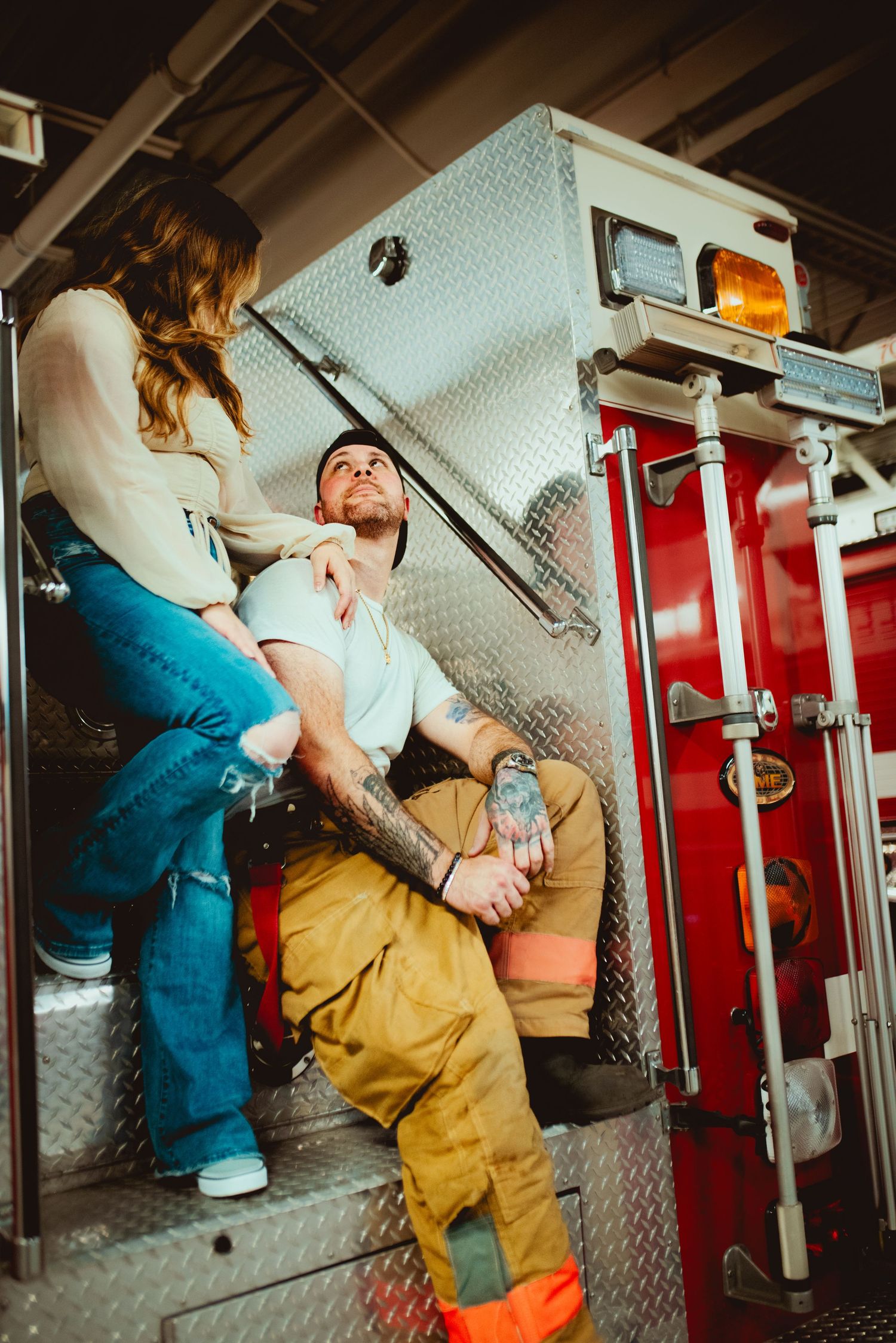 A couple shares a tender moment on the steps of a fire truck.