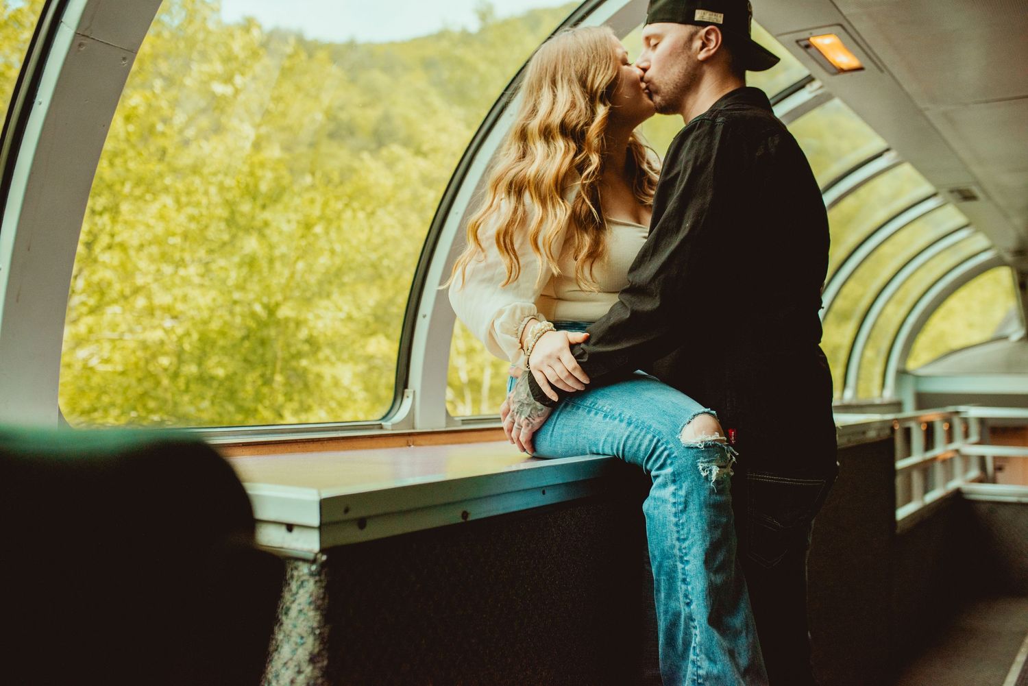 Intimate moment shared between couple in sunlit observation car.