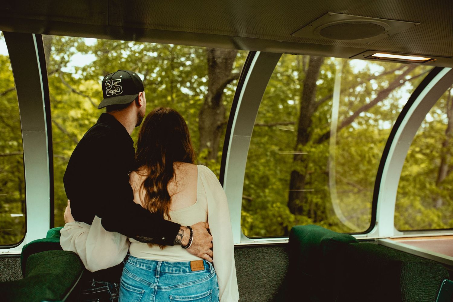 Candid moment captured inside a train car with large curved windows and green upholstery.