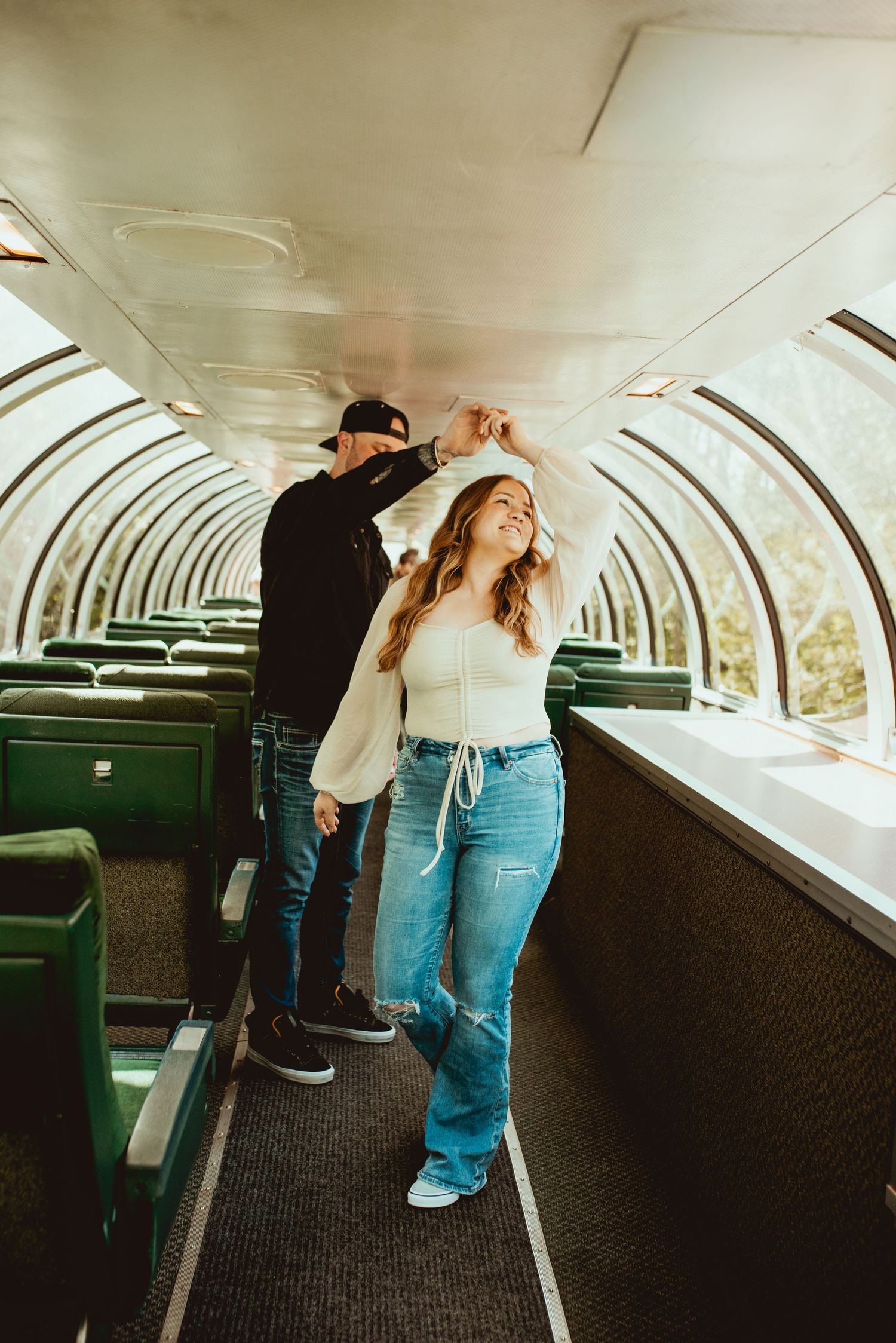 A couple dancing in an empty vintage observation car with curved glass ceiling.