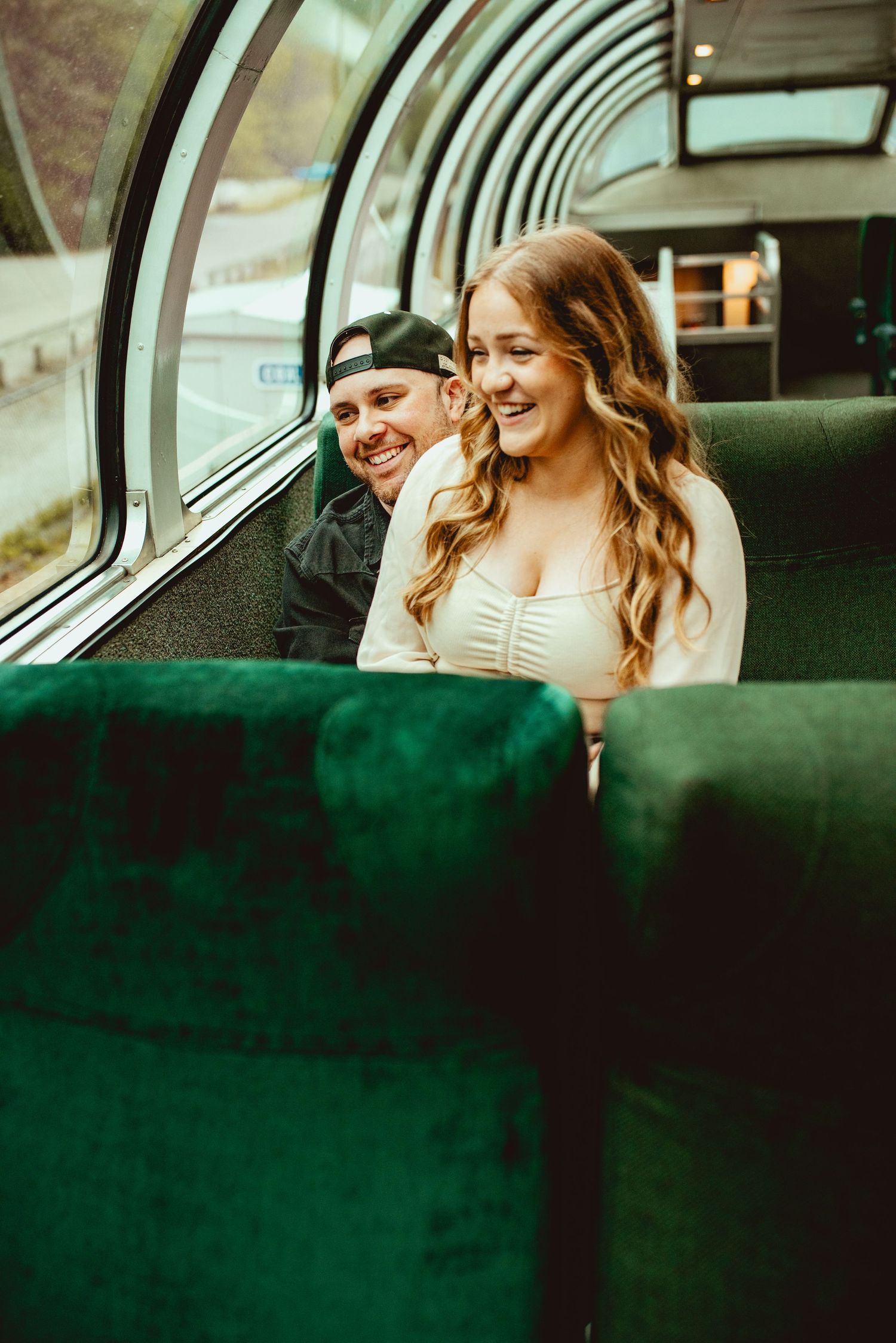 Intimate scene in a train observation car with curved glass ceiling and forest views.